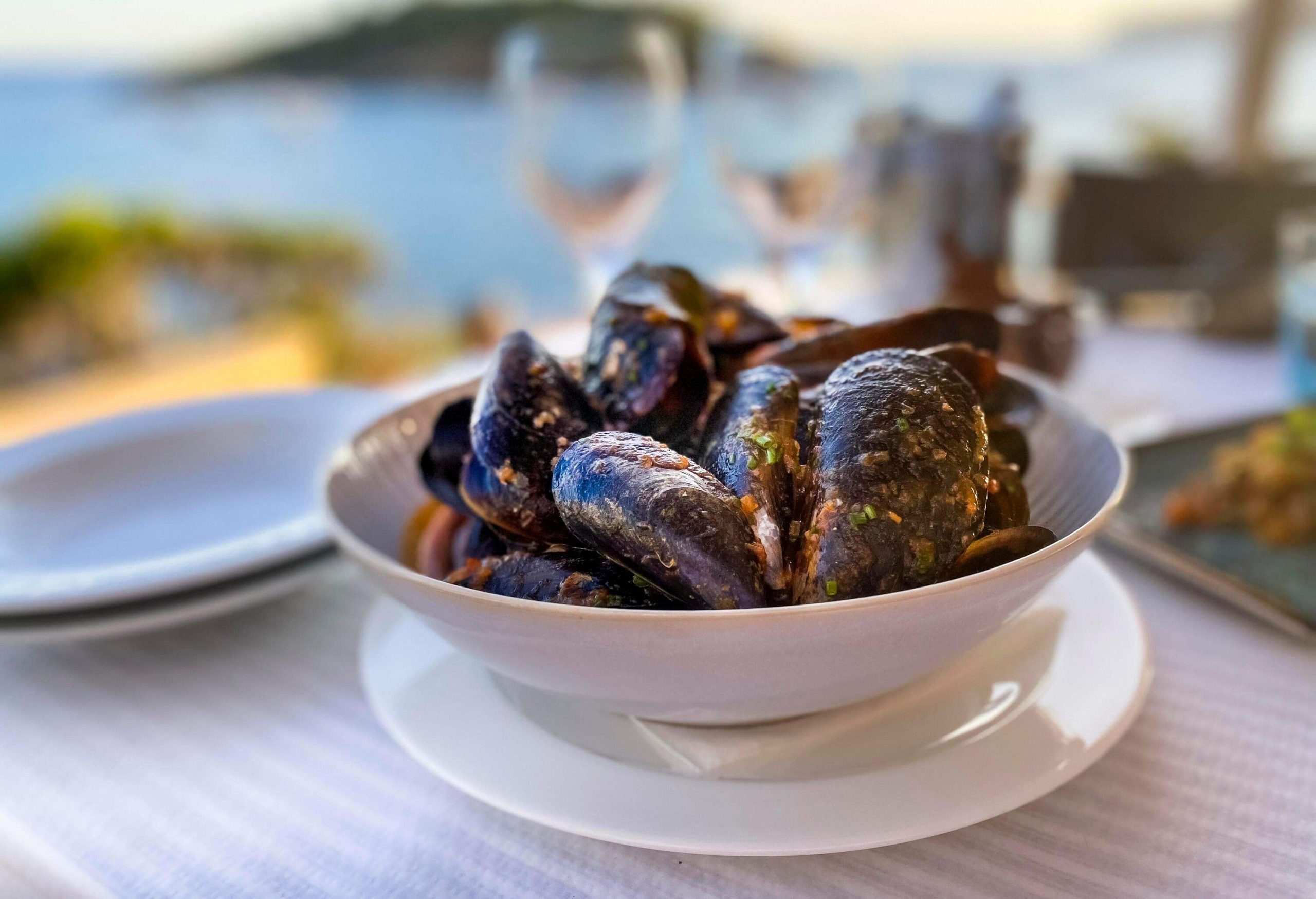 A bowl of delicious mussels served on the table.