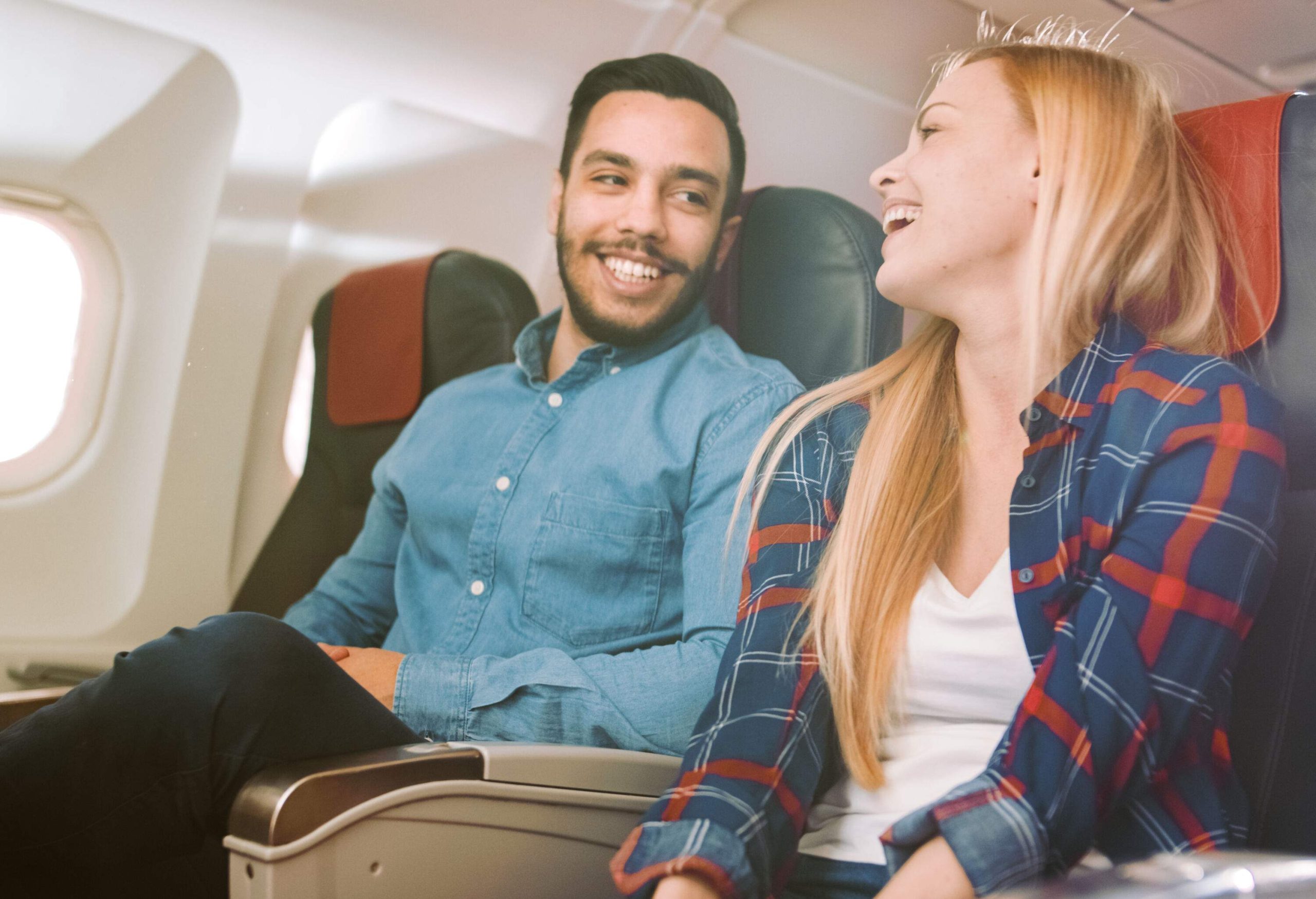 A man and a woman talking and smiling at each other during the flight.