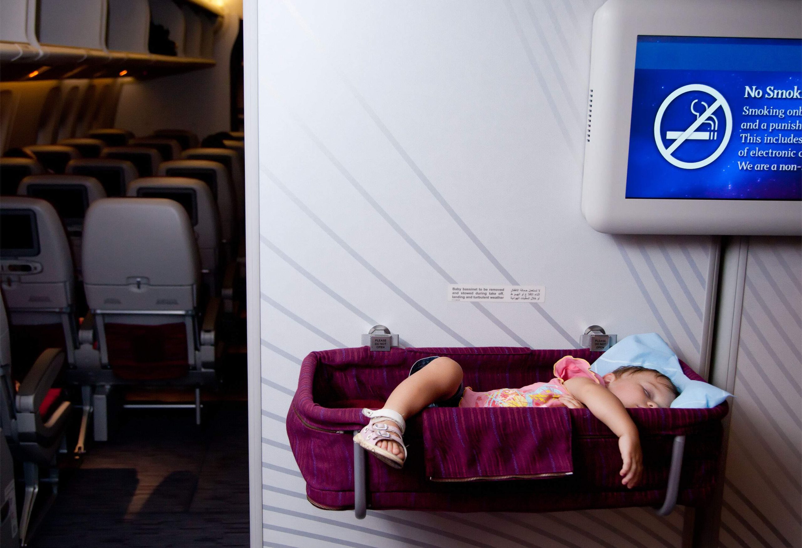 A baby sleeping in a bassinet inside a plane's cabin.