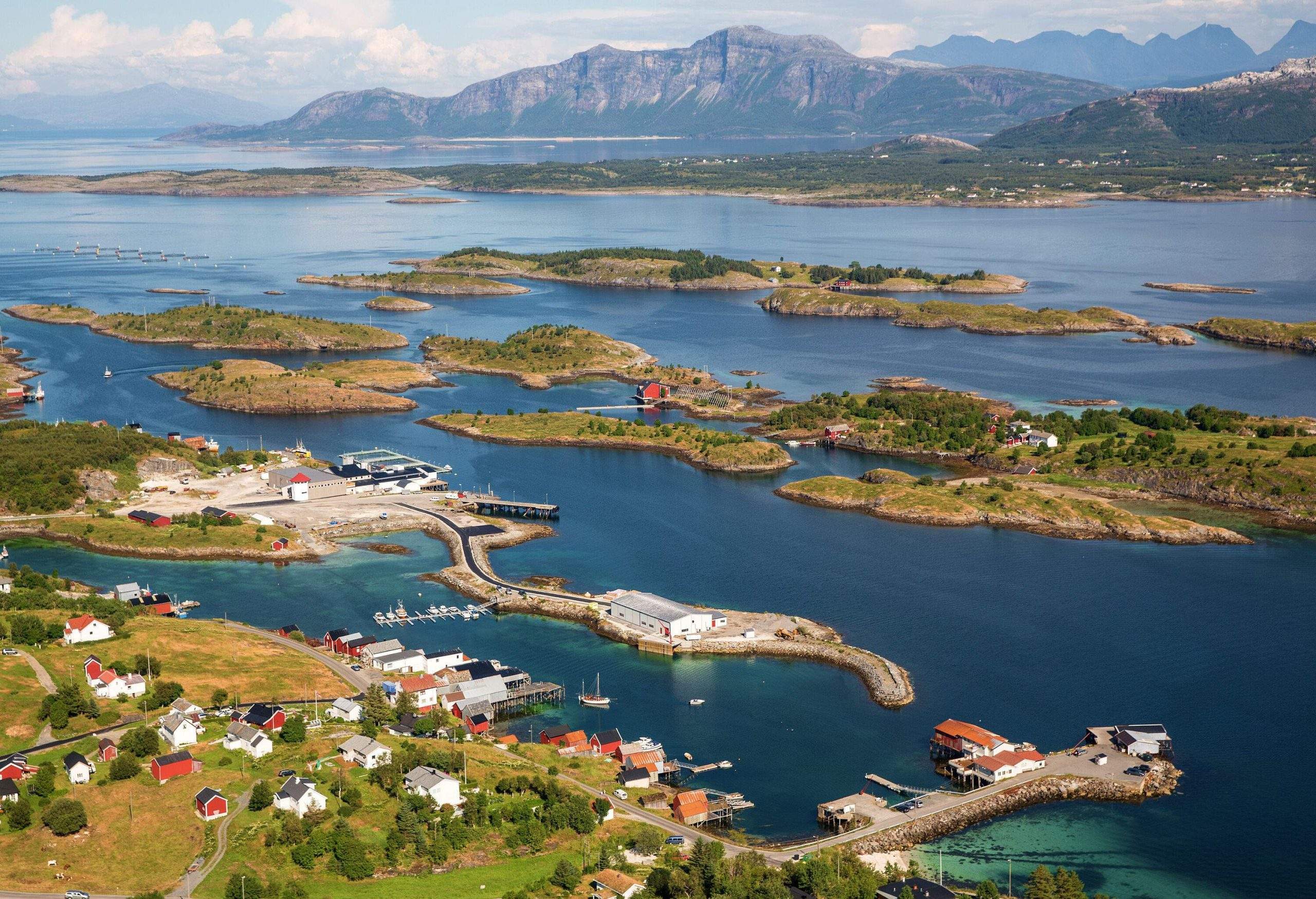 A rural village with a sheltered harbour next to small islands in a lake.