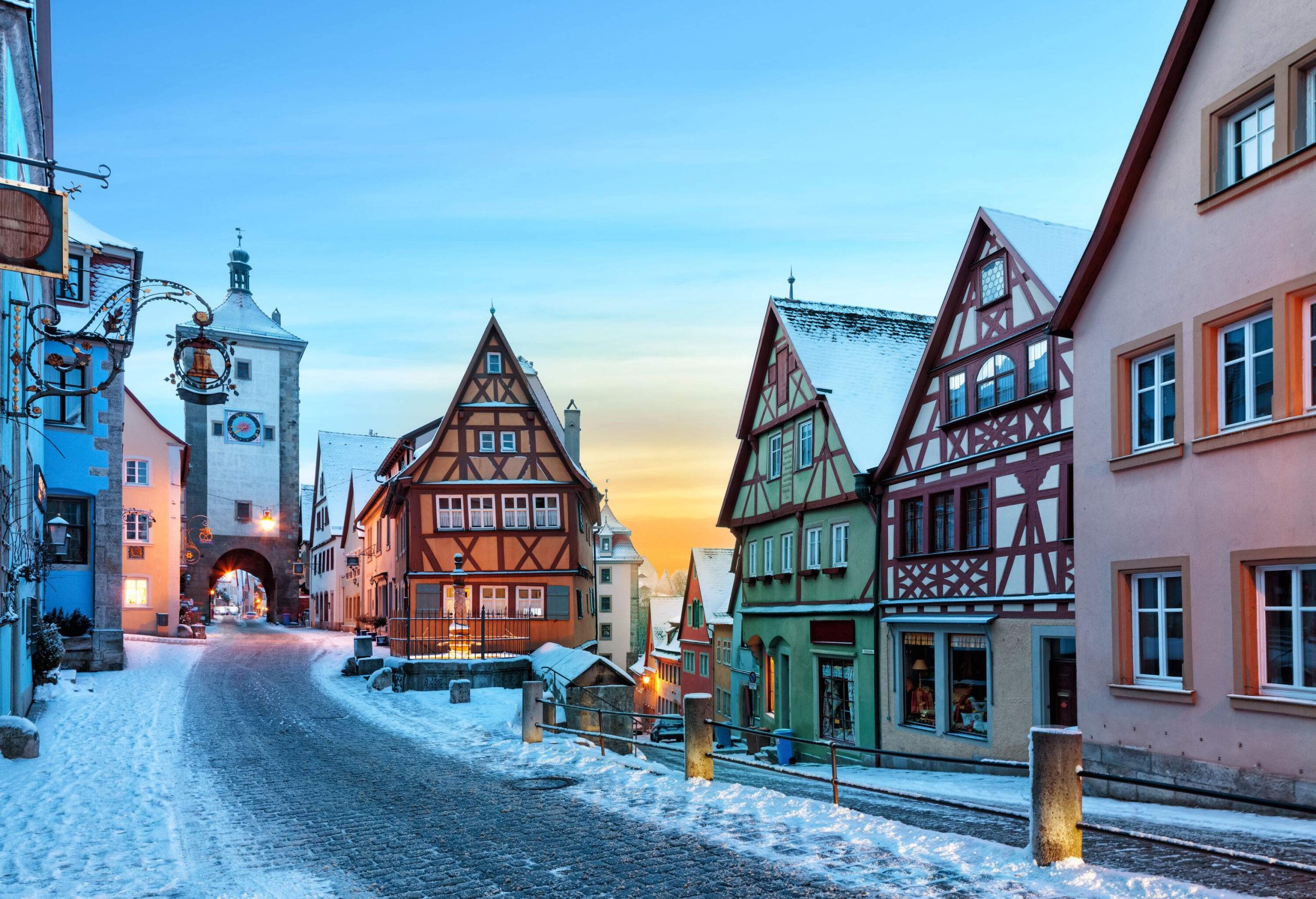 A town that is blanketed in snow and has a road that leads to a gateway.