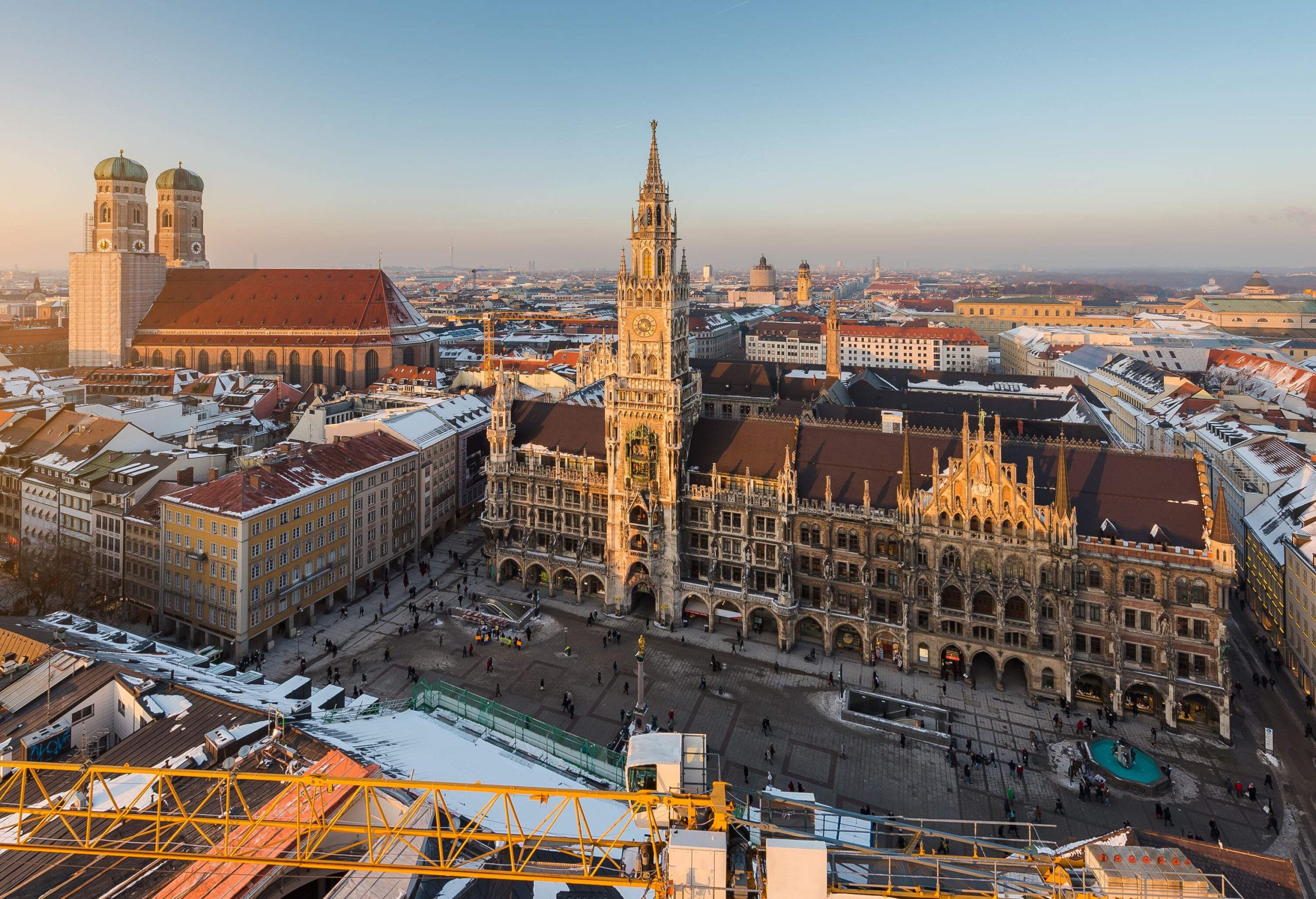 An ornate gothic town hall with a spectacular tower facing the city's main square in the middle of compact tall buildings.