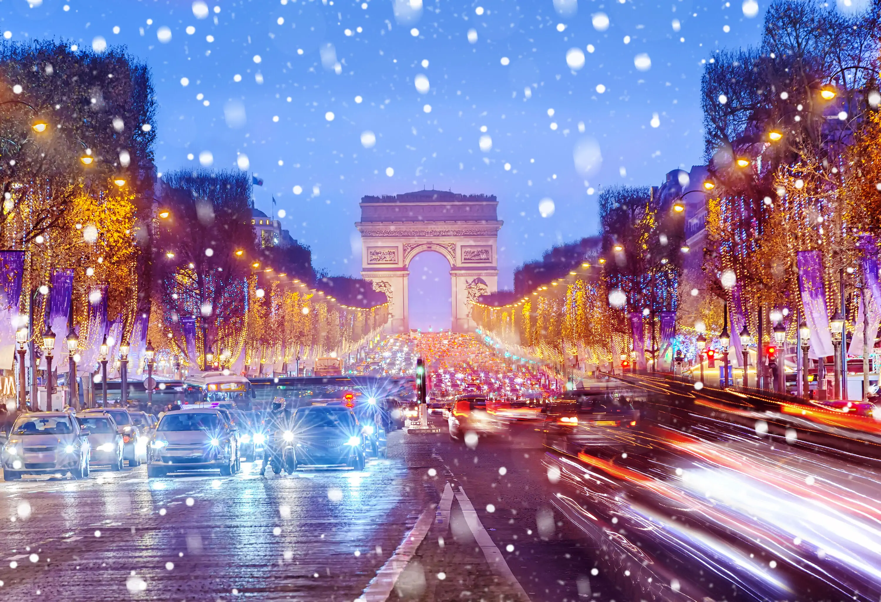 Snow falling over the busy streets of Paris with the Arch of Triumph in the distance.