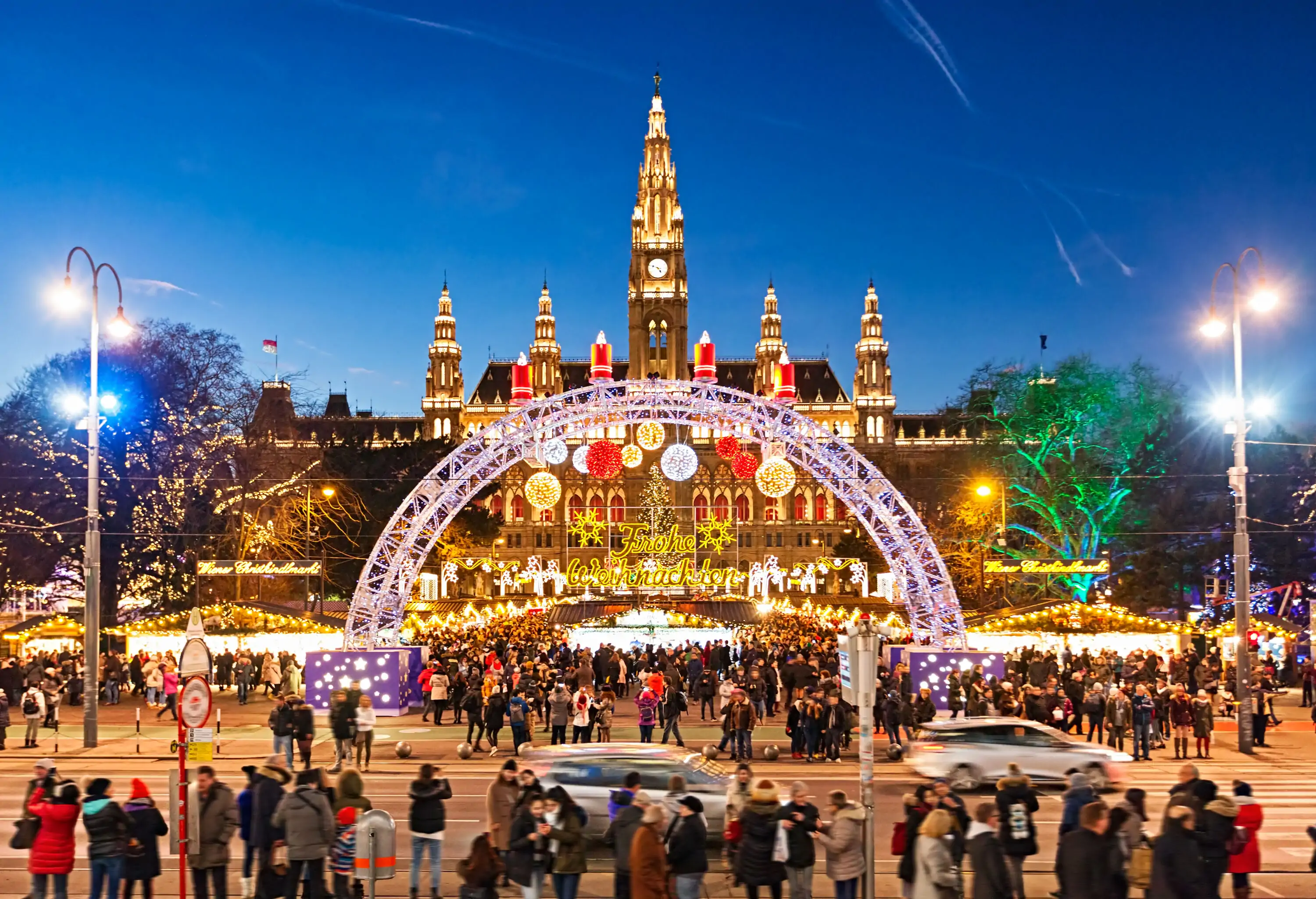 A spectacular Christmas market entrance arch set against the stunning grandeur of an illuminated old town hall.