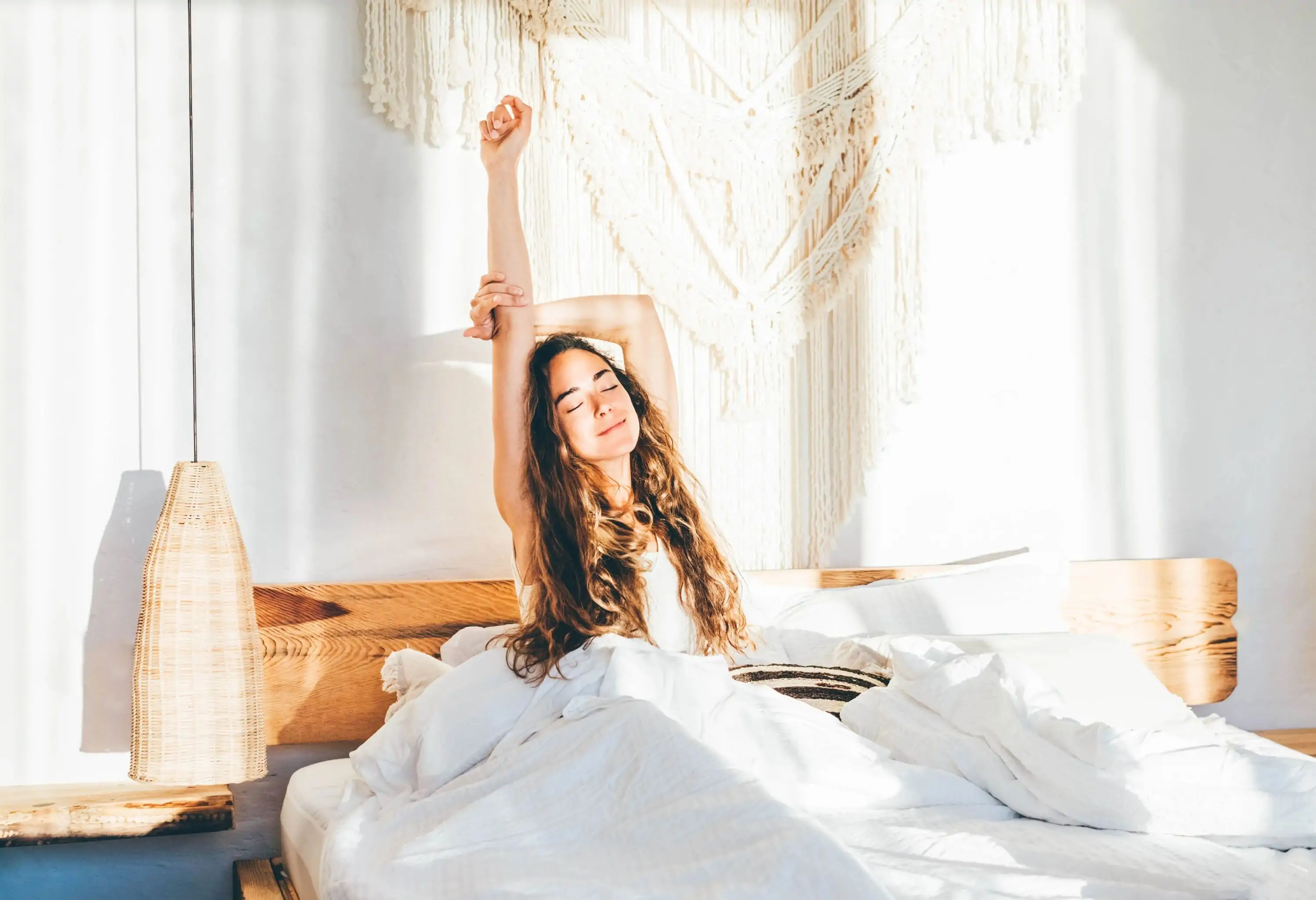 Woman stretching hands in bed.