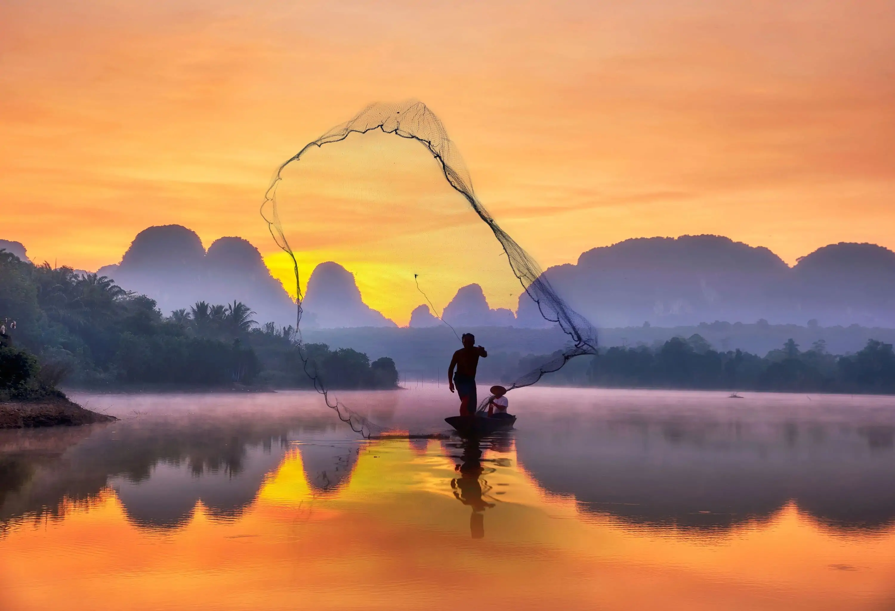 Silhouette fisherman A silhouette fisherman throw a net to catch a fish in a river with morning sun.