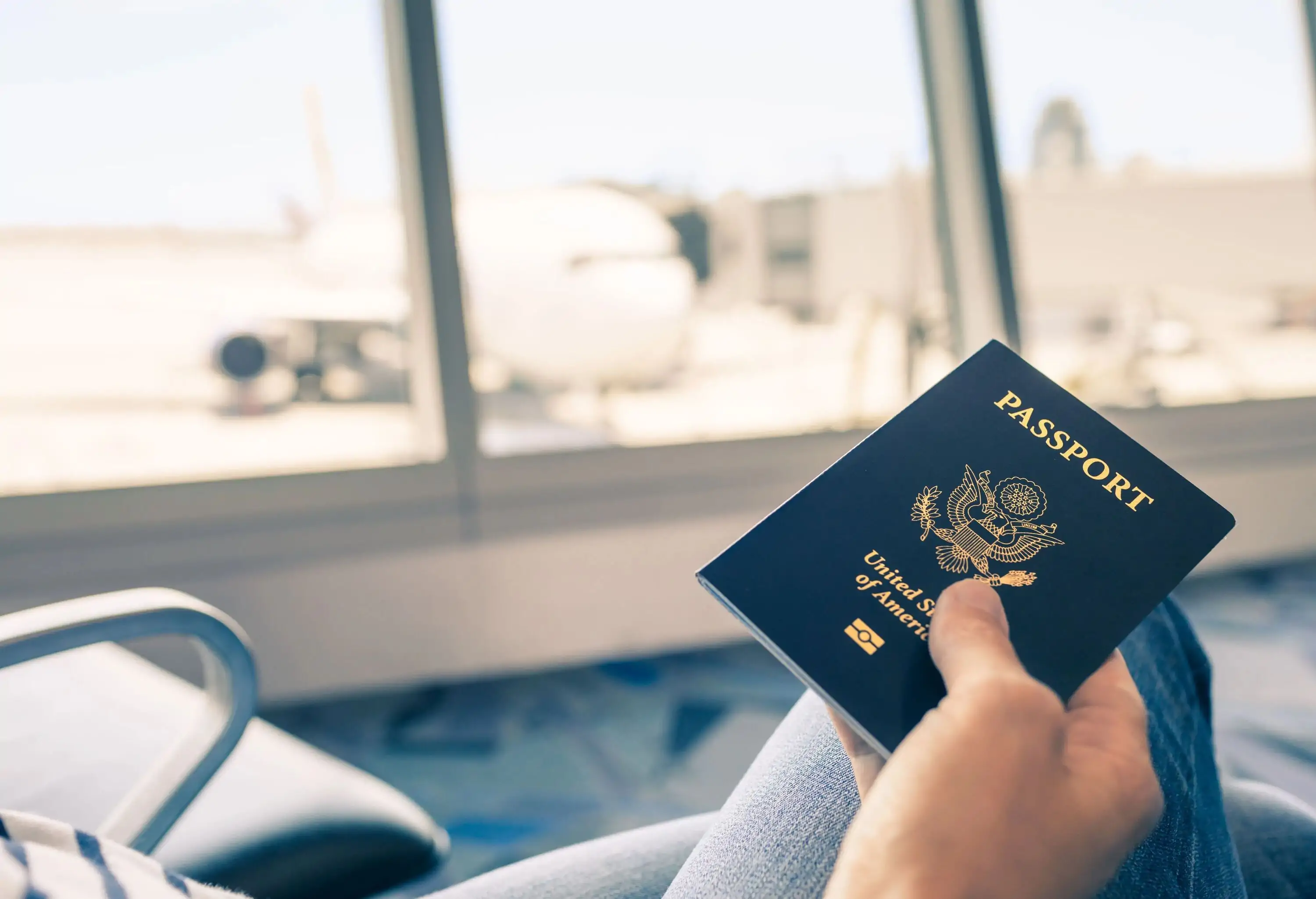 Traveler at airport holding United States passport in hand.