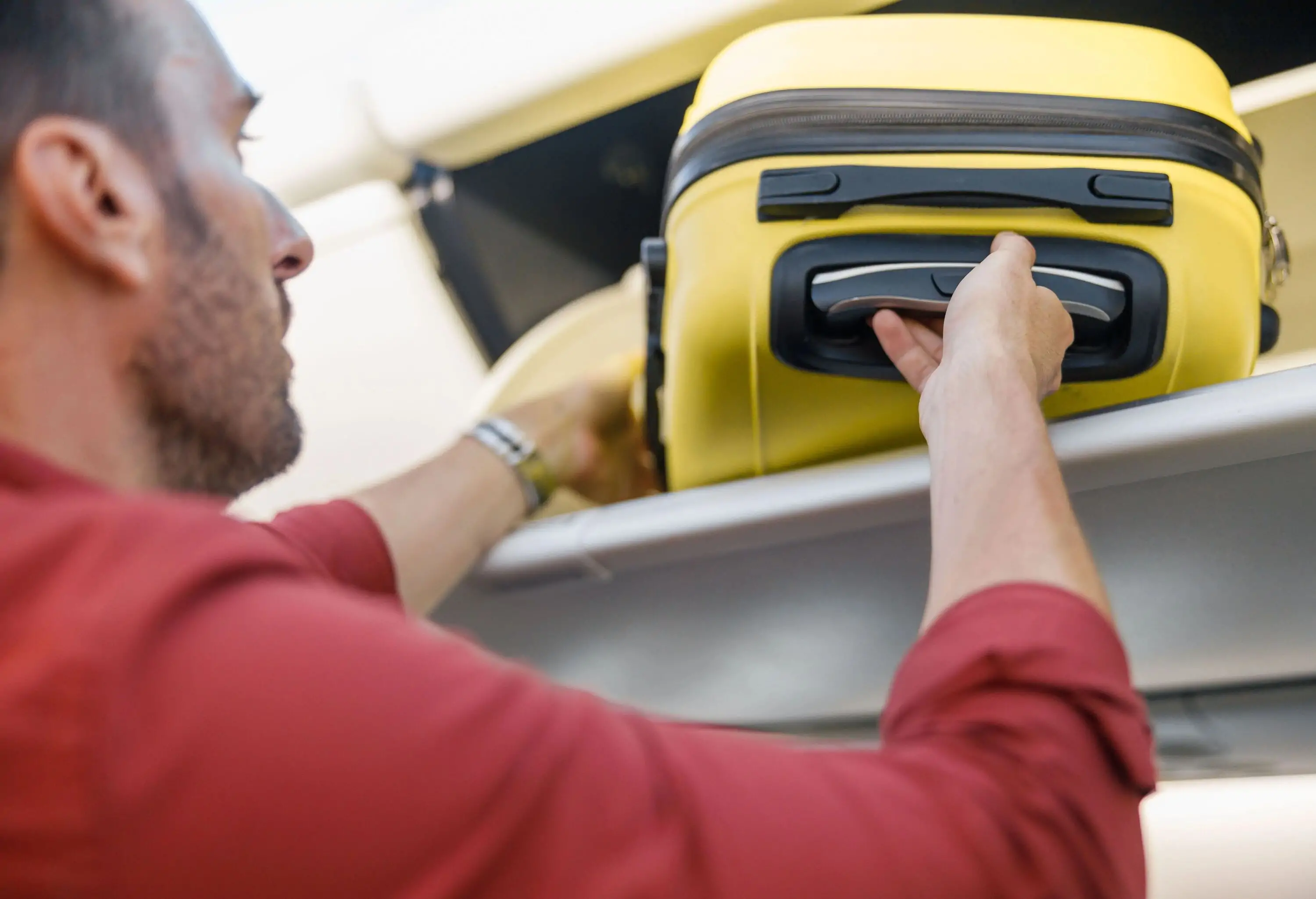 A men placing his carry-on suitcase in the overhead bin