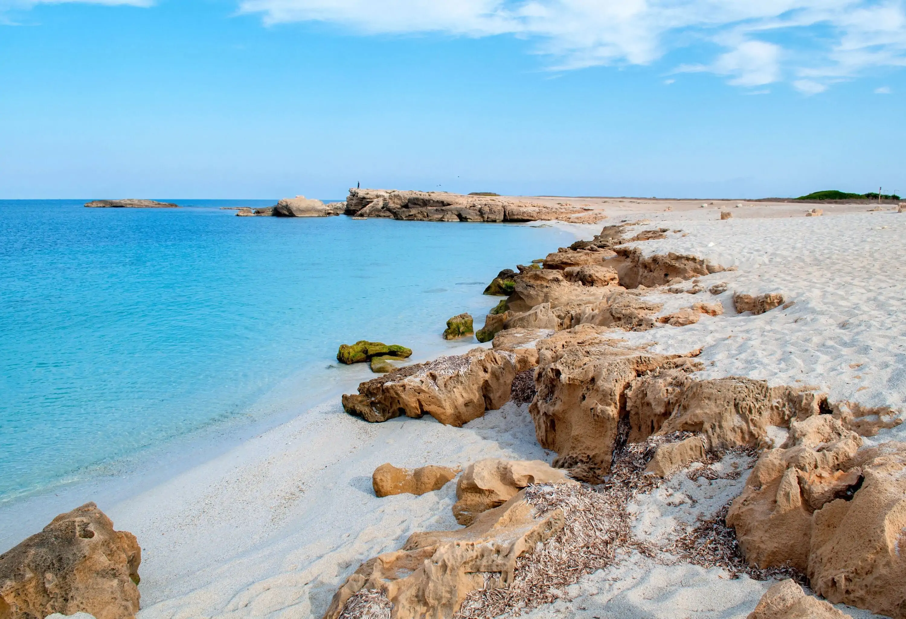 A rocky white fine sand beach with crystalline turquoise calm water.