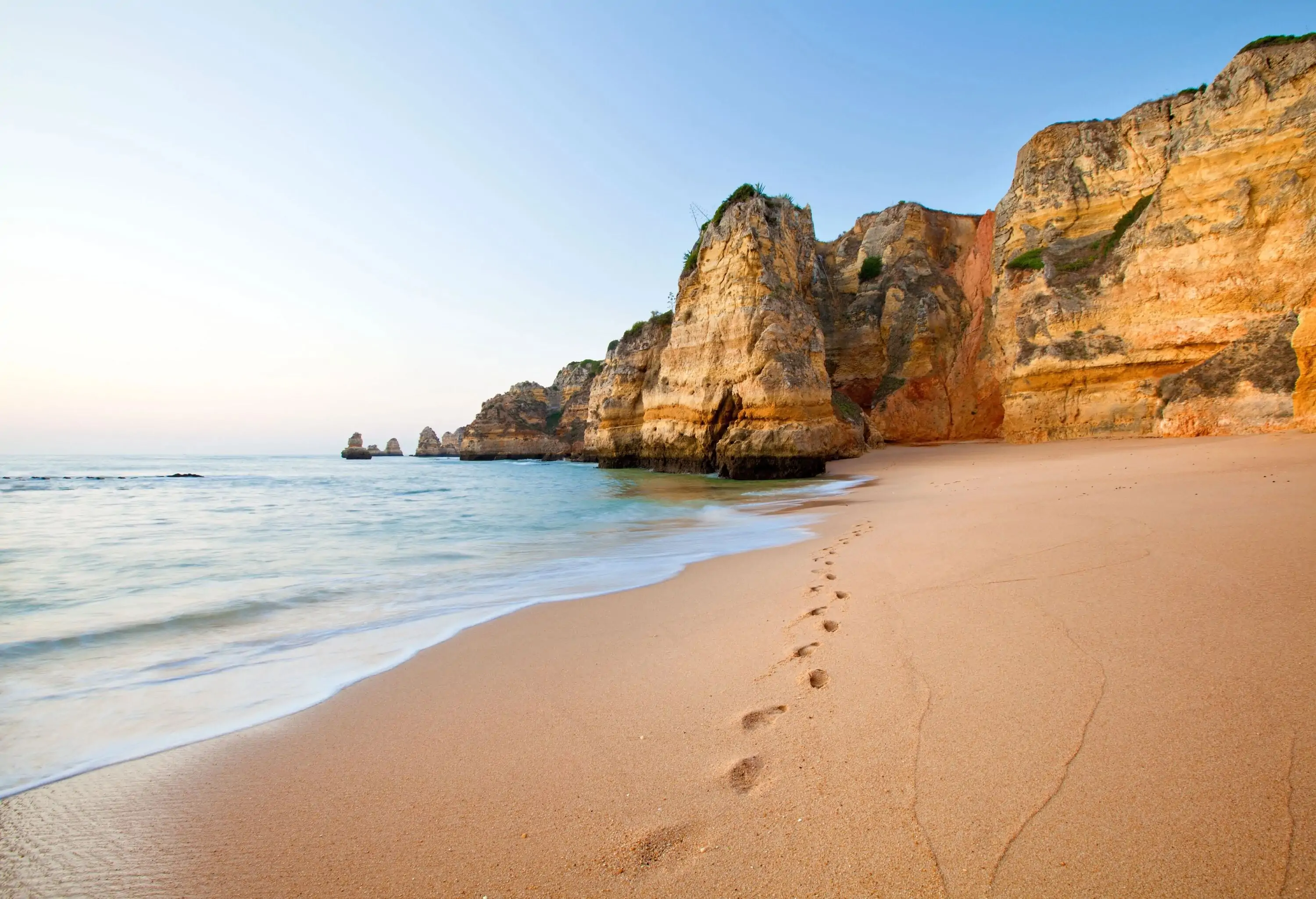 A track of footprints on the beach's soaked sand.