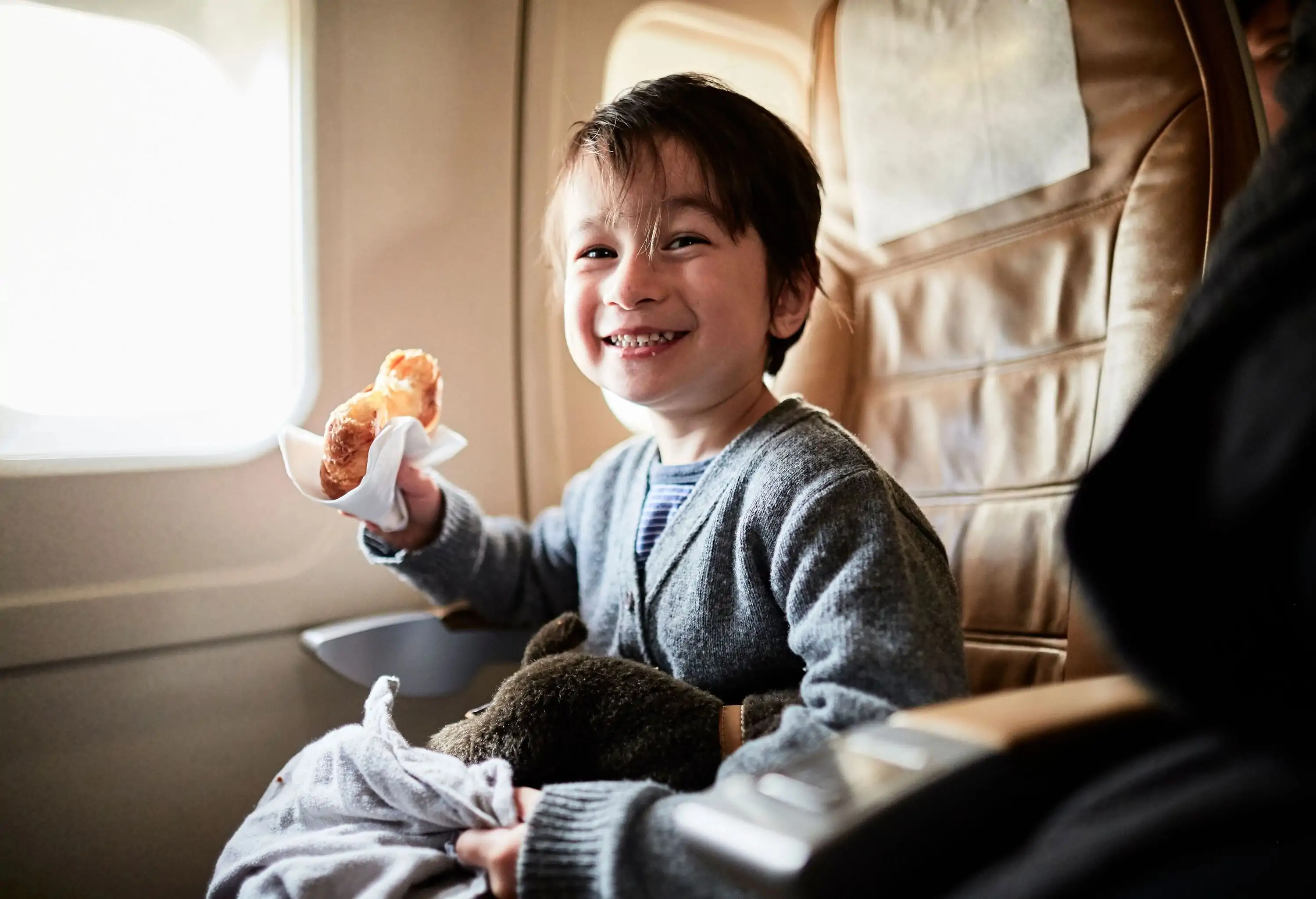 a little boy eating while sitting in the airplane seat