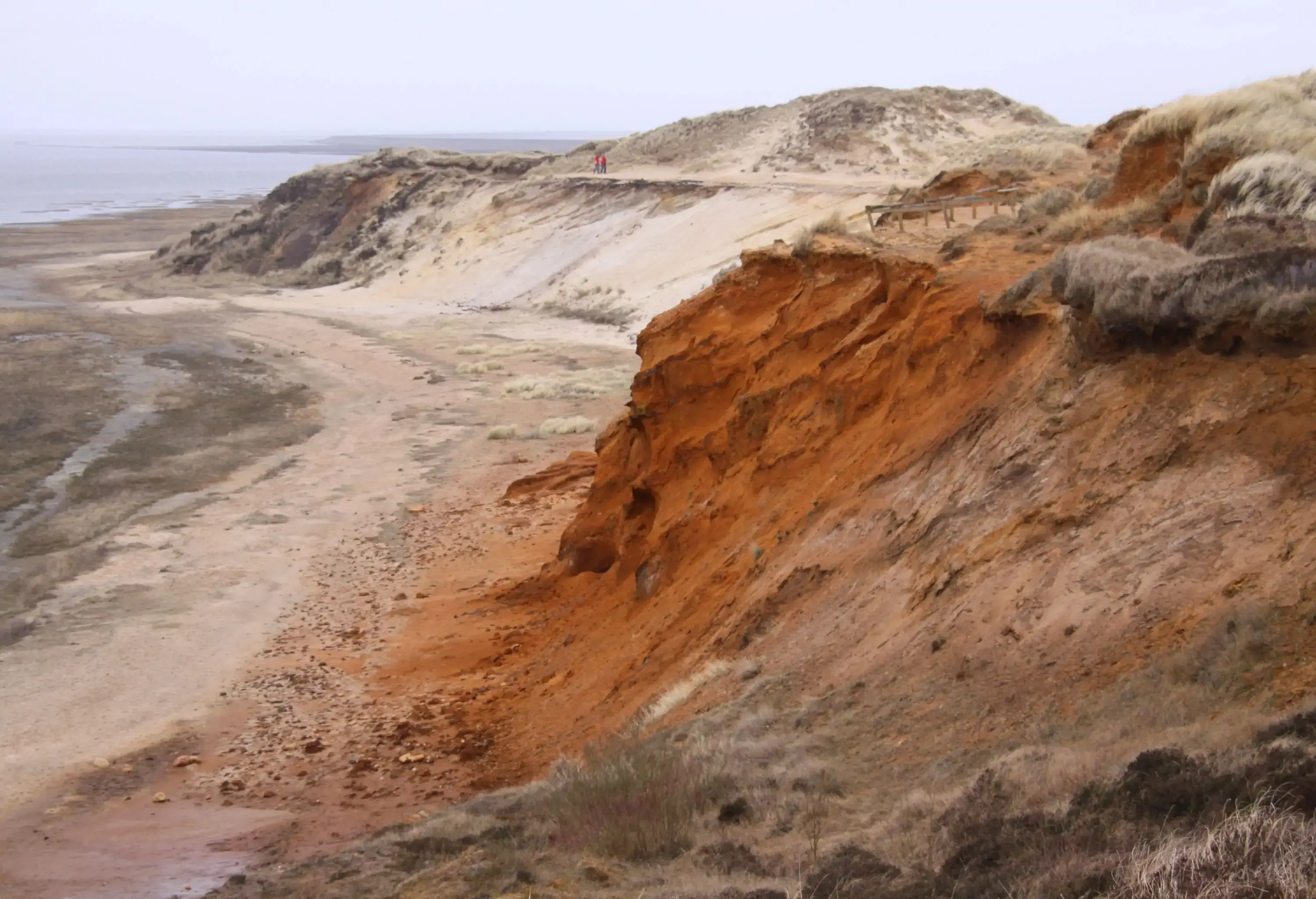 Fascinating rugged cliffs made of various layers of the soil of different colours alongside a sea.