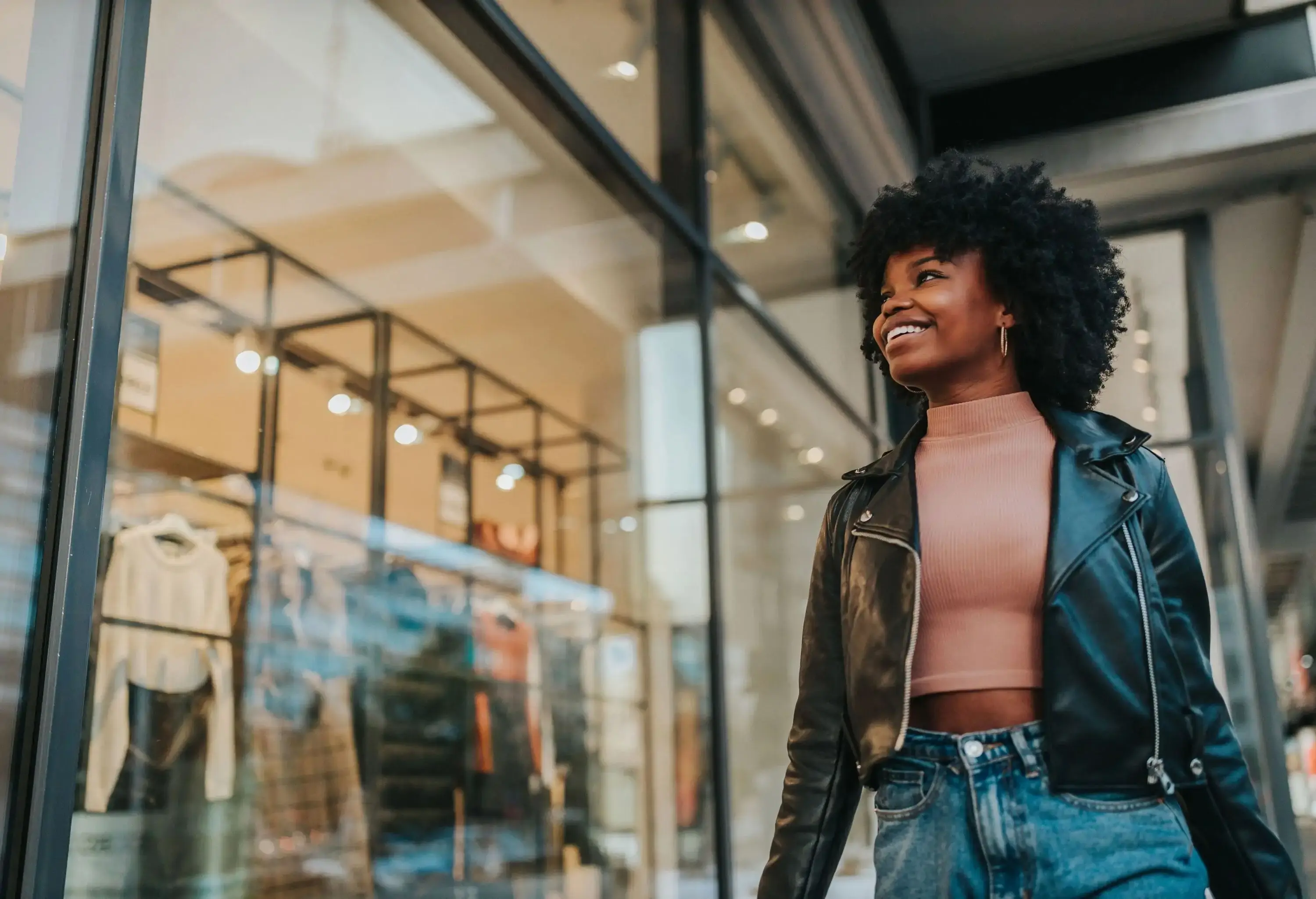 A cheerful woman stands outside a boutique, gazing at the shop window. 