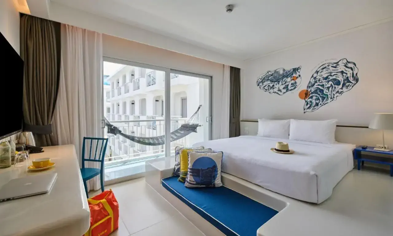 A modern hotel room in white and blue tones with a hammock hanging on the balcony
