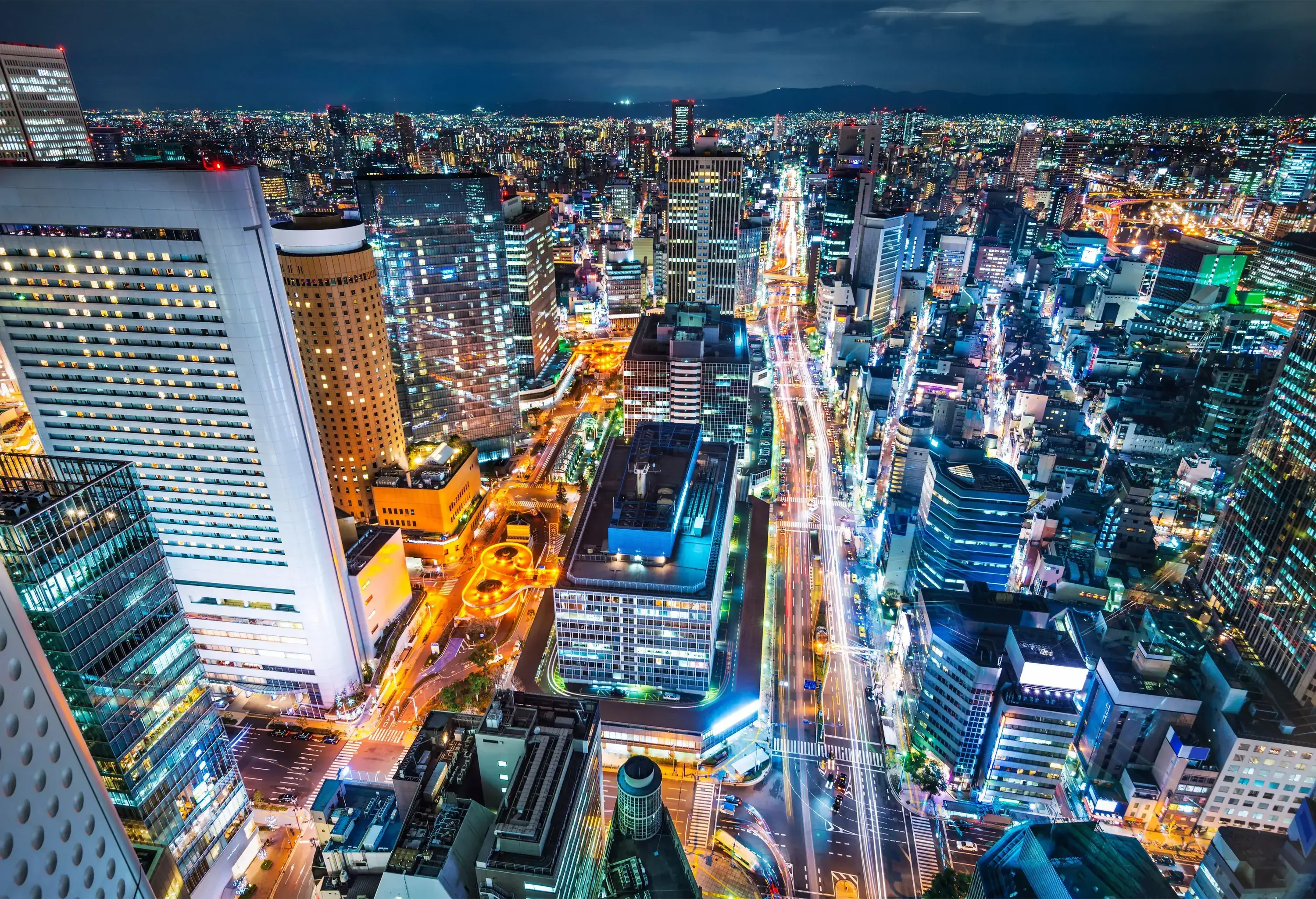 A night-time view of a high-rise buildings illuminated by city lights.