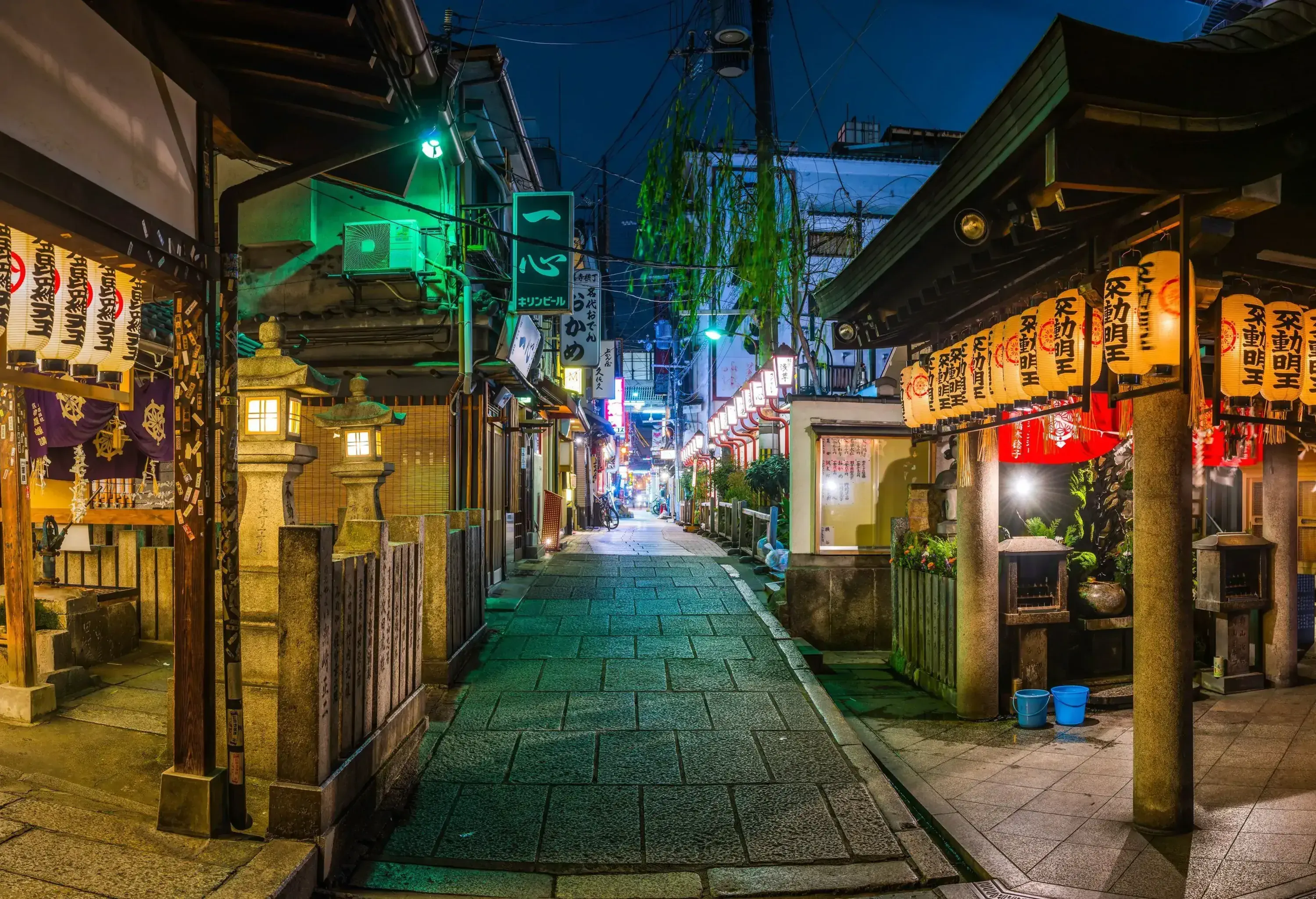Warm lamplight delicately bathes a serene, paved alleyway lined with quaint buildings.