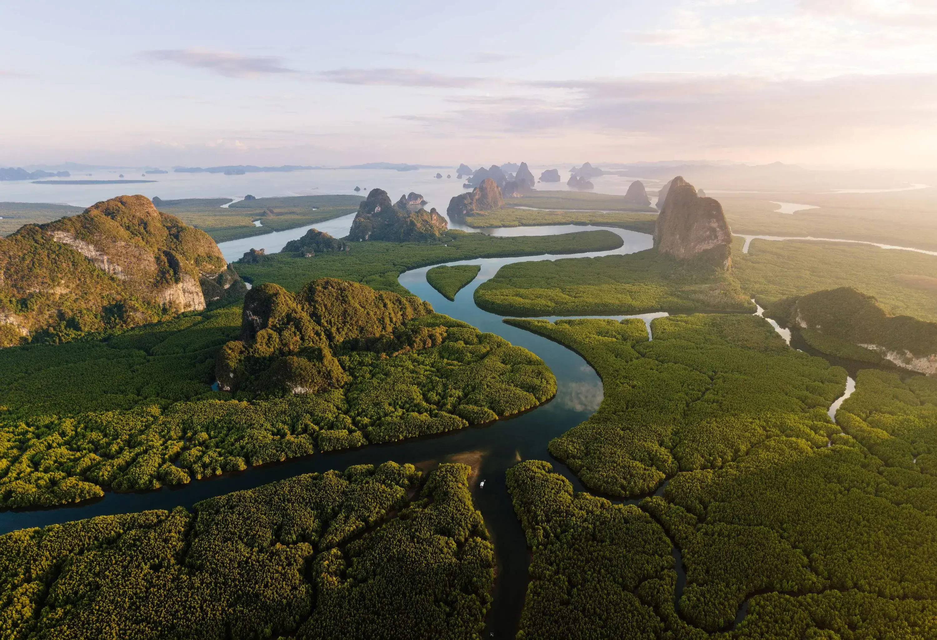 A winding stream across a terrain of dense forest and rock formations that leads to a bay.
