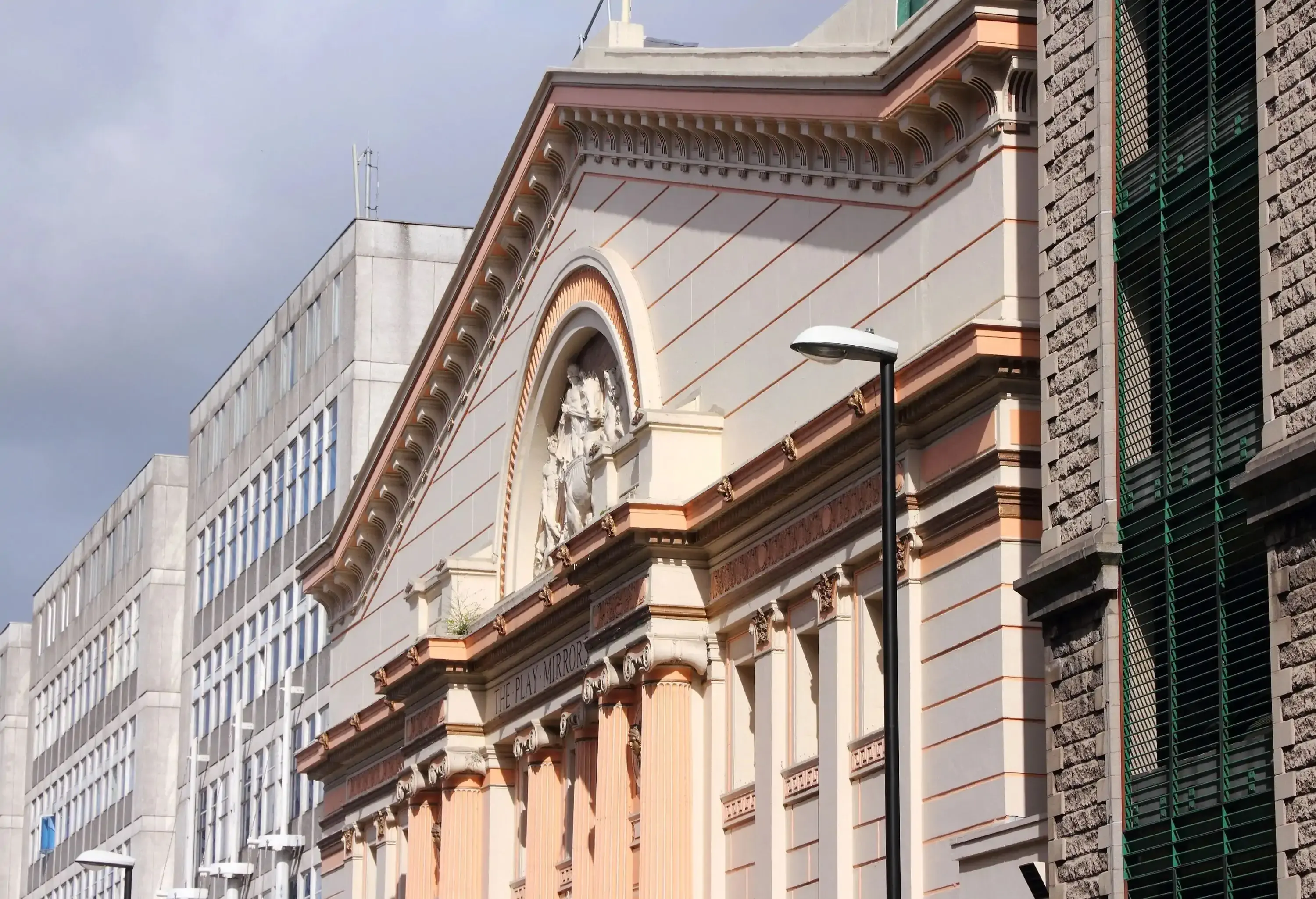 A detailed façade of a building with carvings inside a semi-circular arch in the pediment.