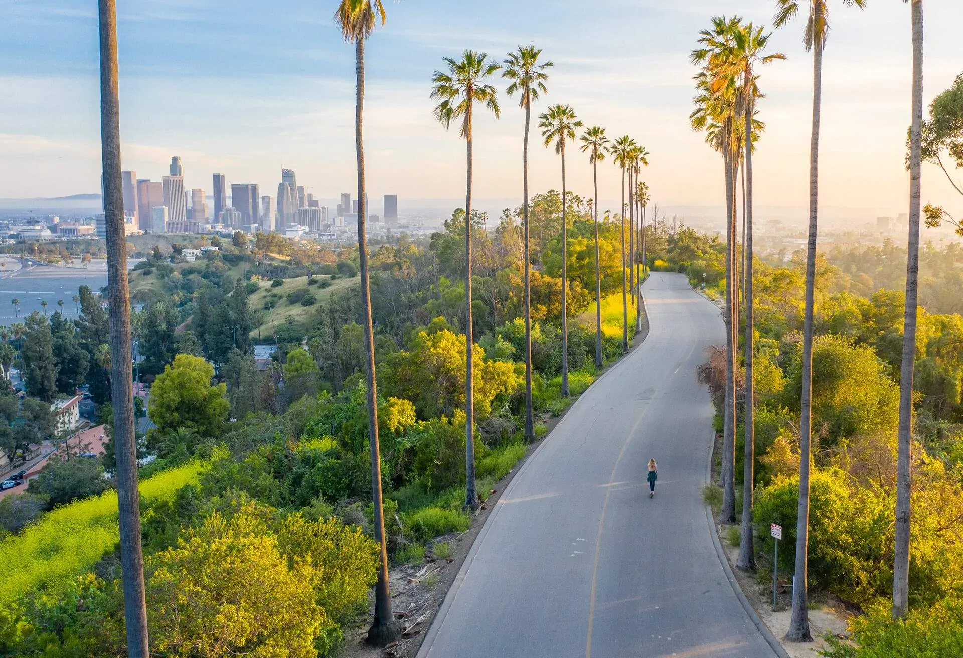 Drone shot of a woman walking down a street toward Downtown Los Angeles, California, Los Angeles