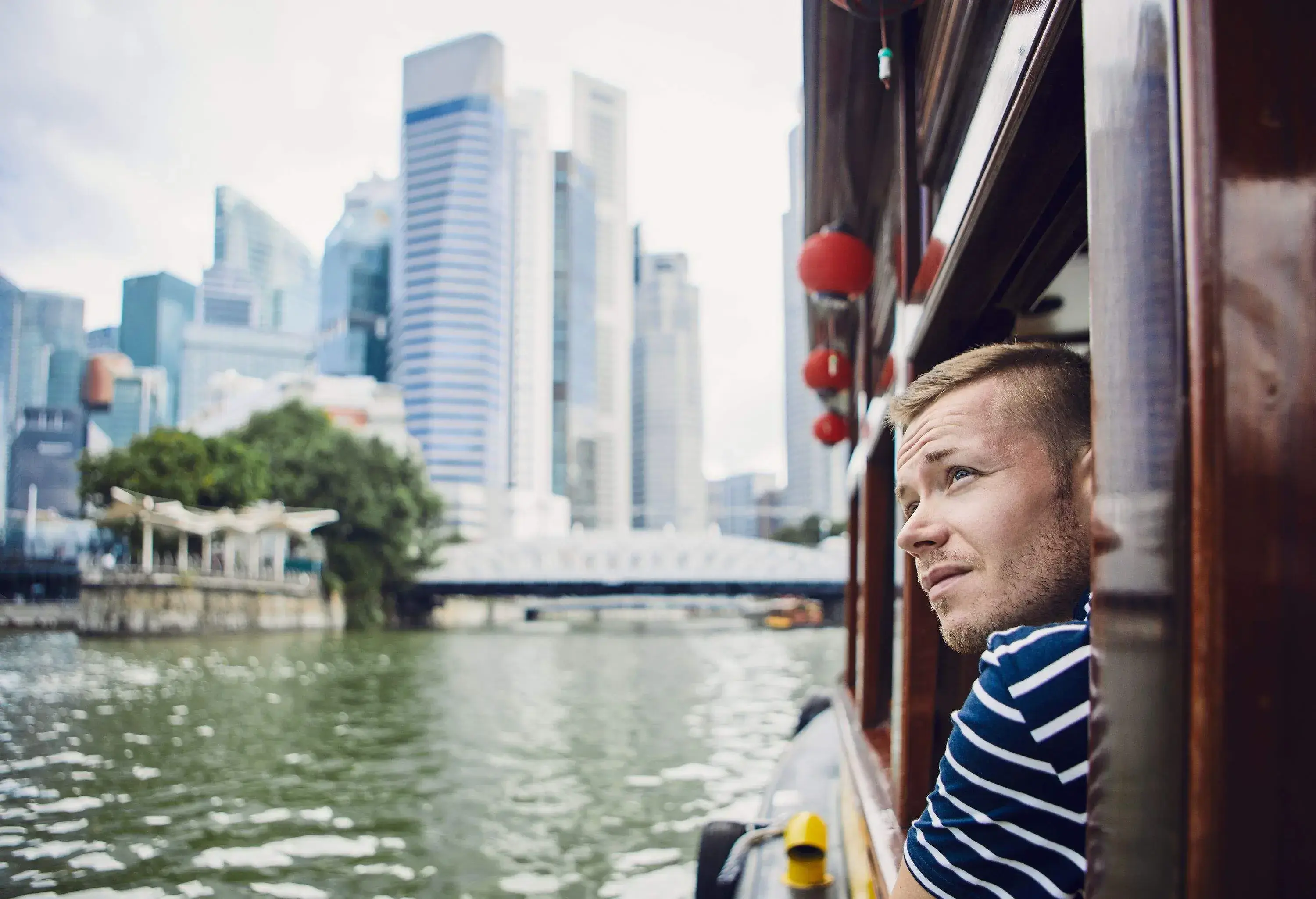 A curious person peeks through the window of a ferry, gazing in awe at the surrounding buildings that paint a vibrant tapestry of the cityscape.