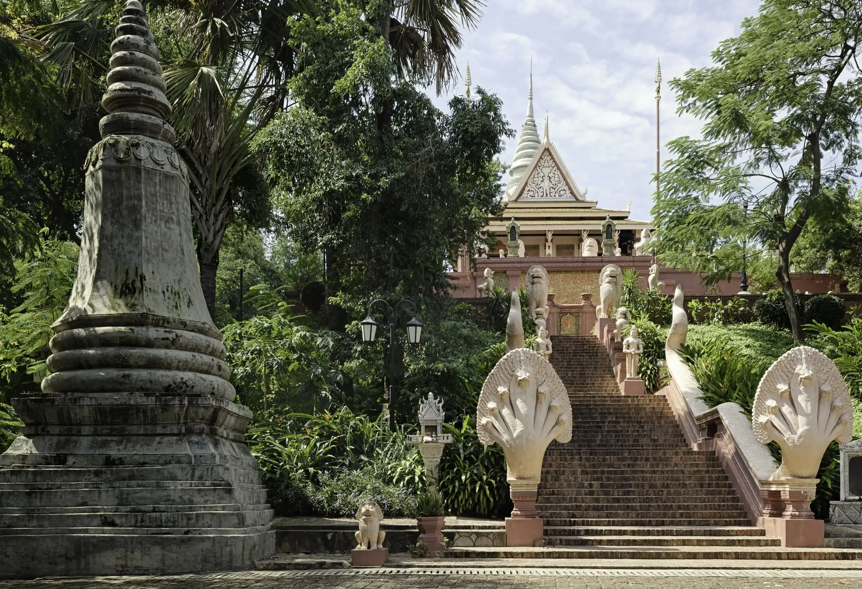 A grand staircase surrounded by lush gardens and trees that leads to a Buddhist temple.