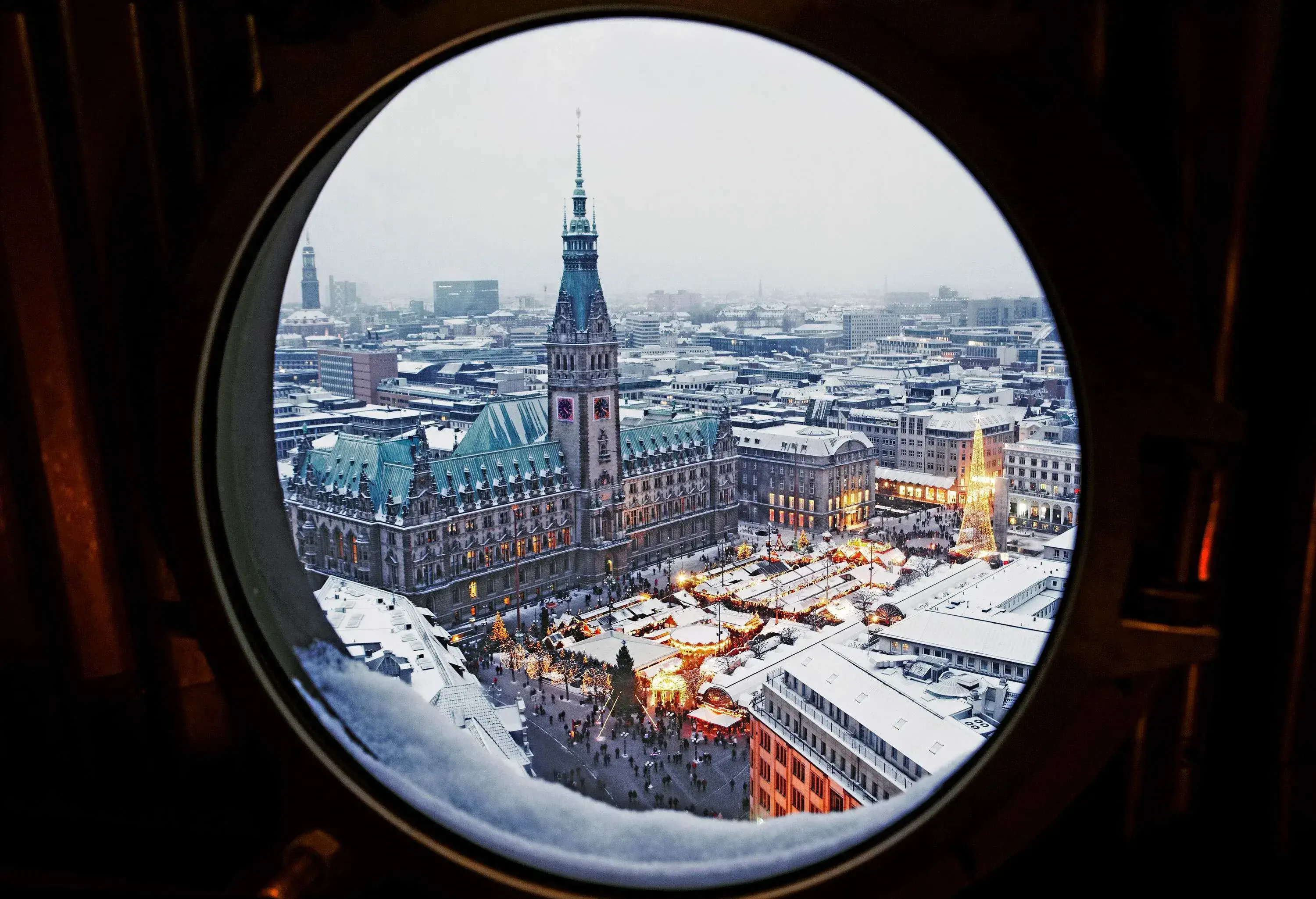 A marketplace illuminated by dazzling Christmas lights from a porthole window.