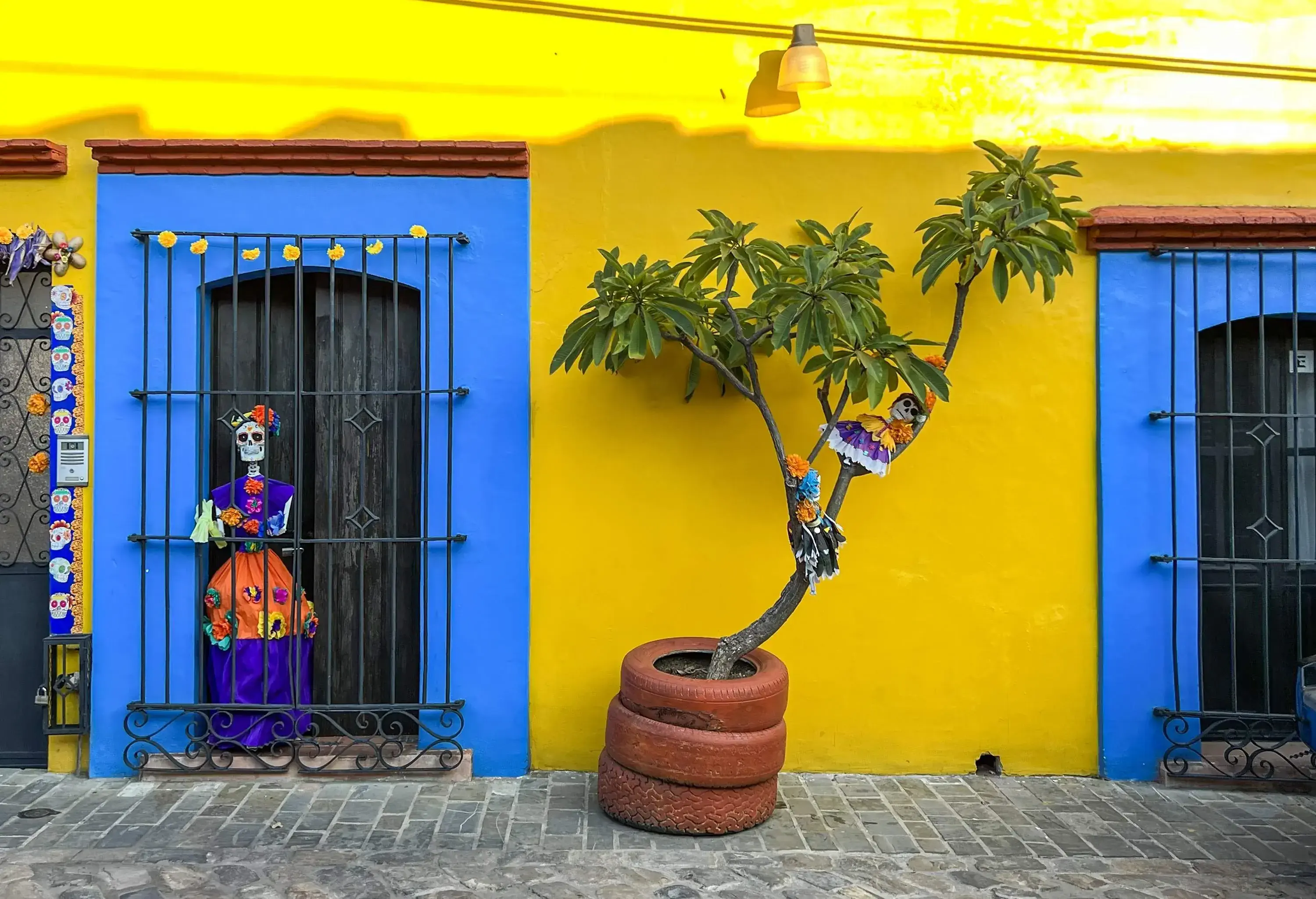 A yellow colonial building decorated with Dia de Muertos artifacts