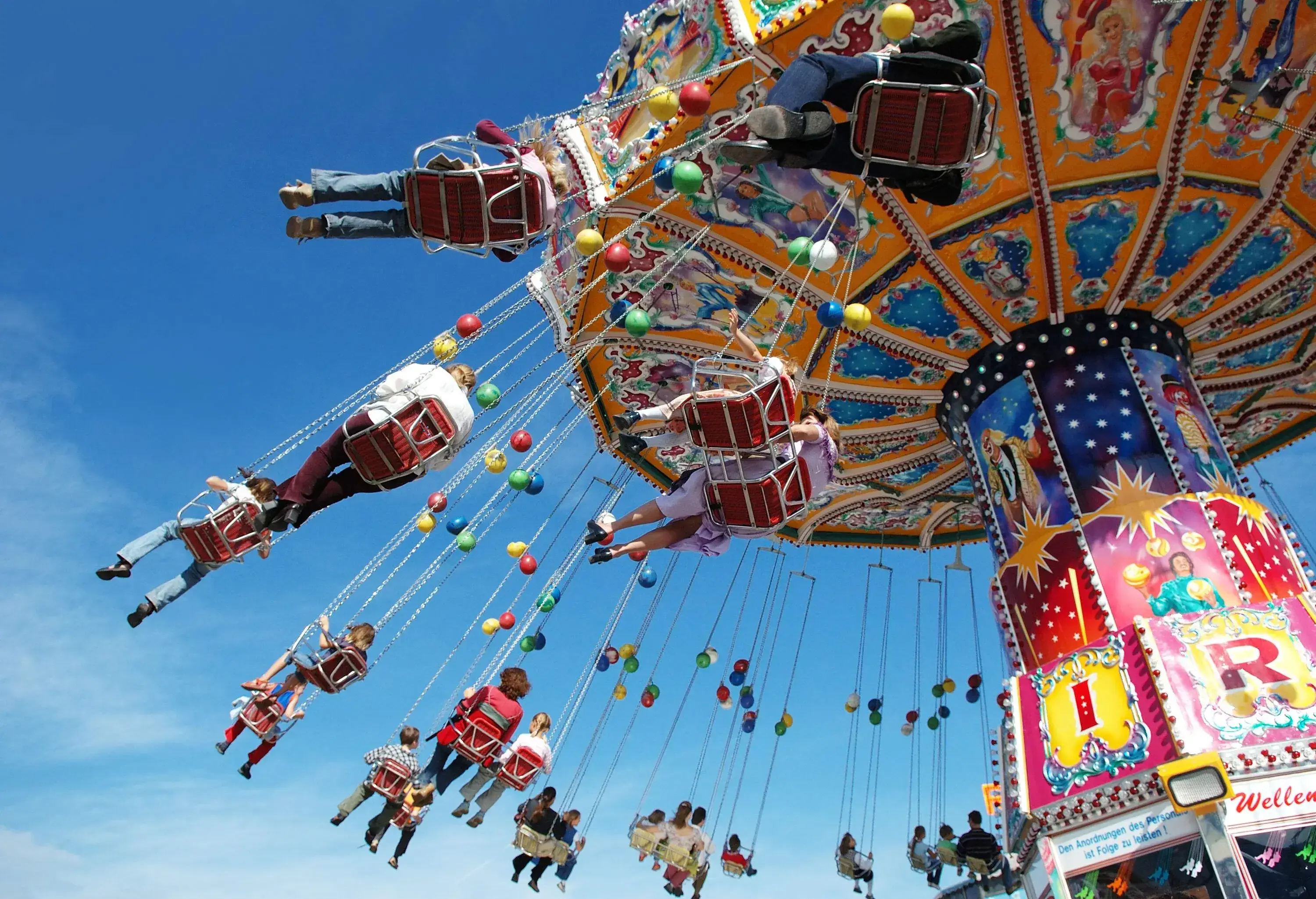 People of various ages ride on a colourful swing carousel.