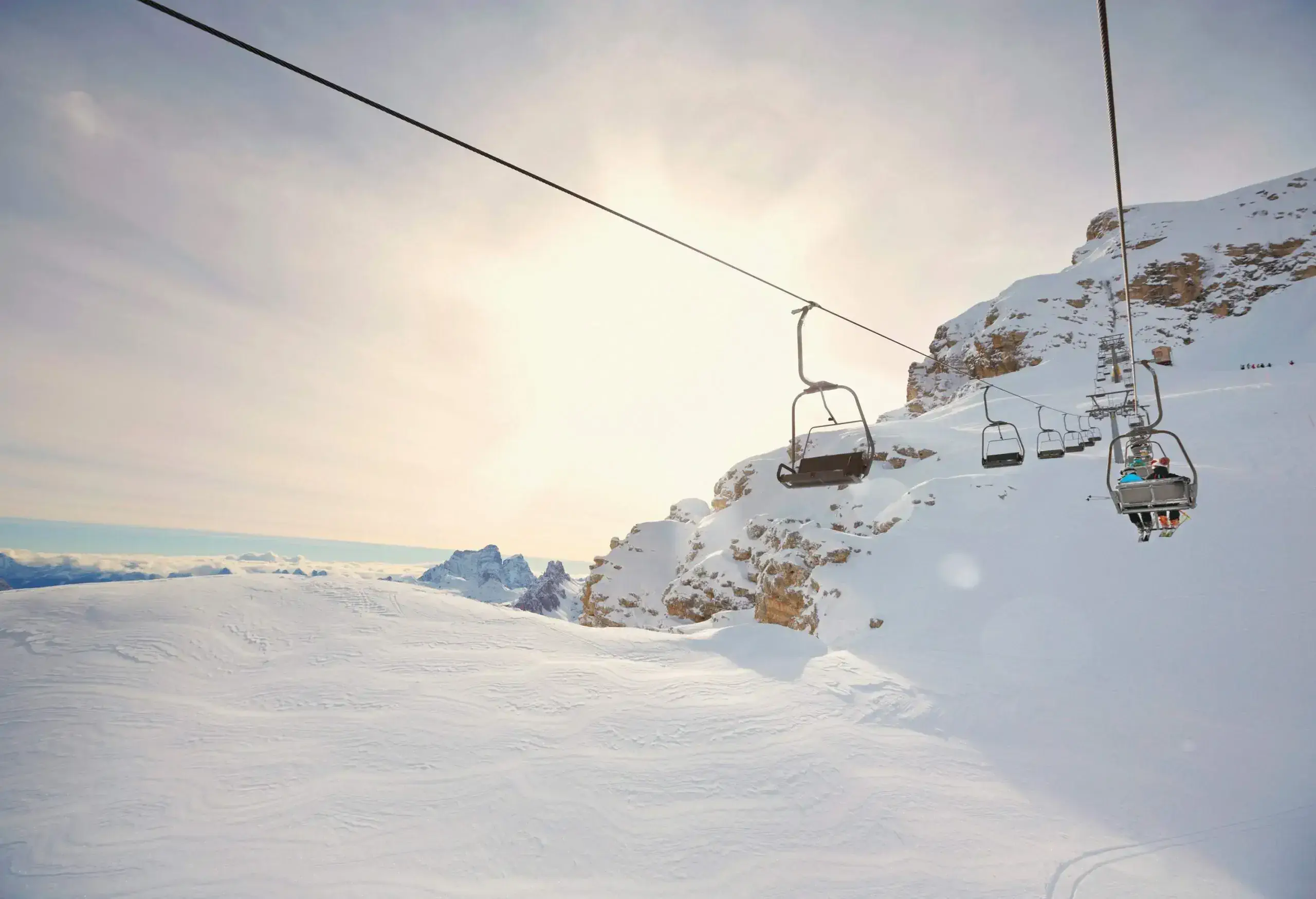People on the ski chairlift above deep powder snowland.