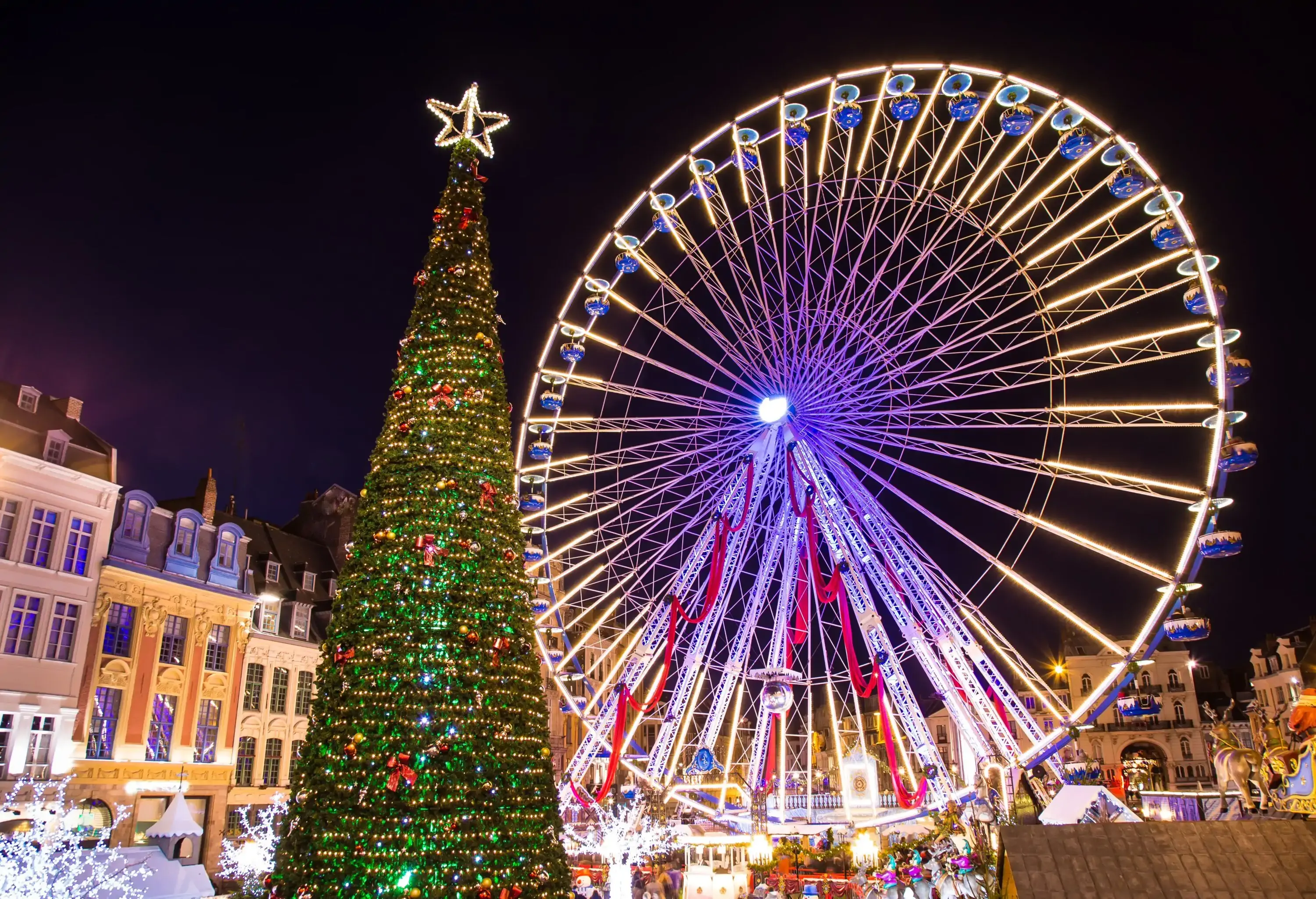 Christmas tree and ferris wheel illuminated at night in Lille Xmas market