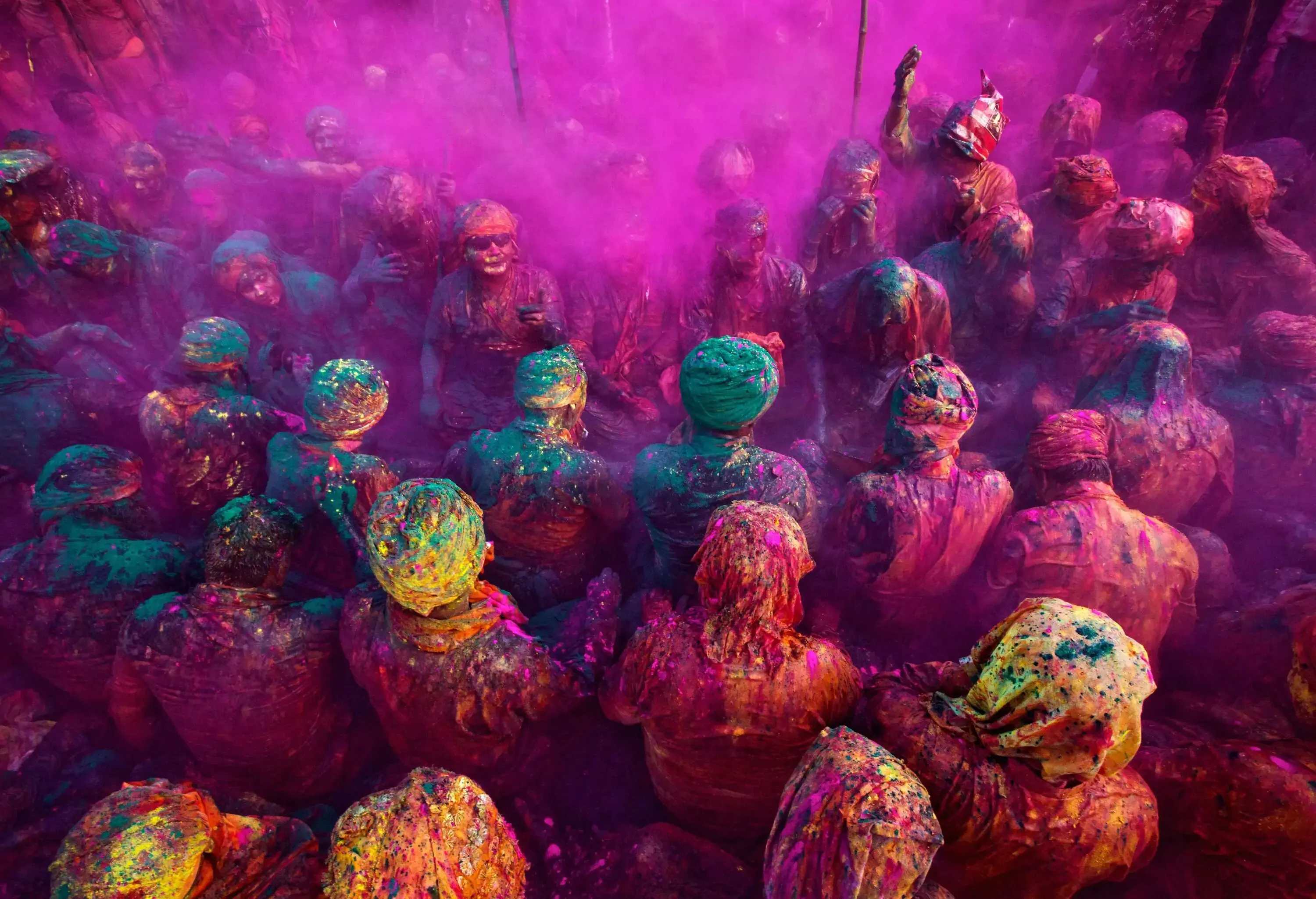 A group of people showered with bright colours of paint.