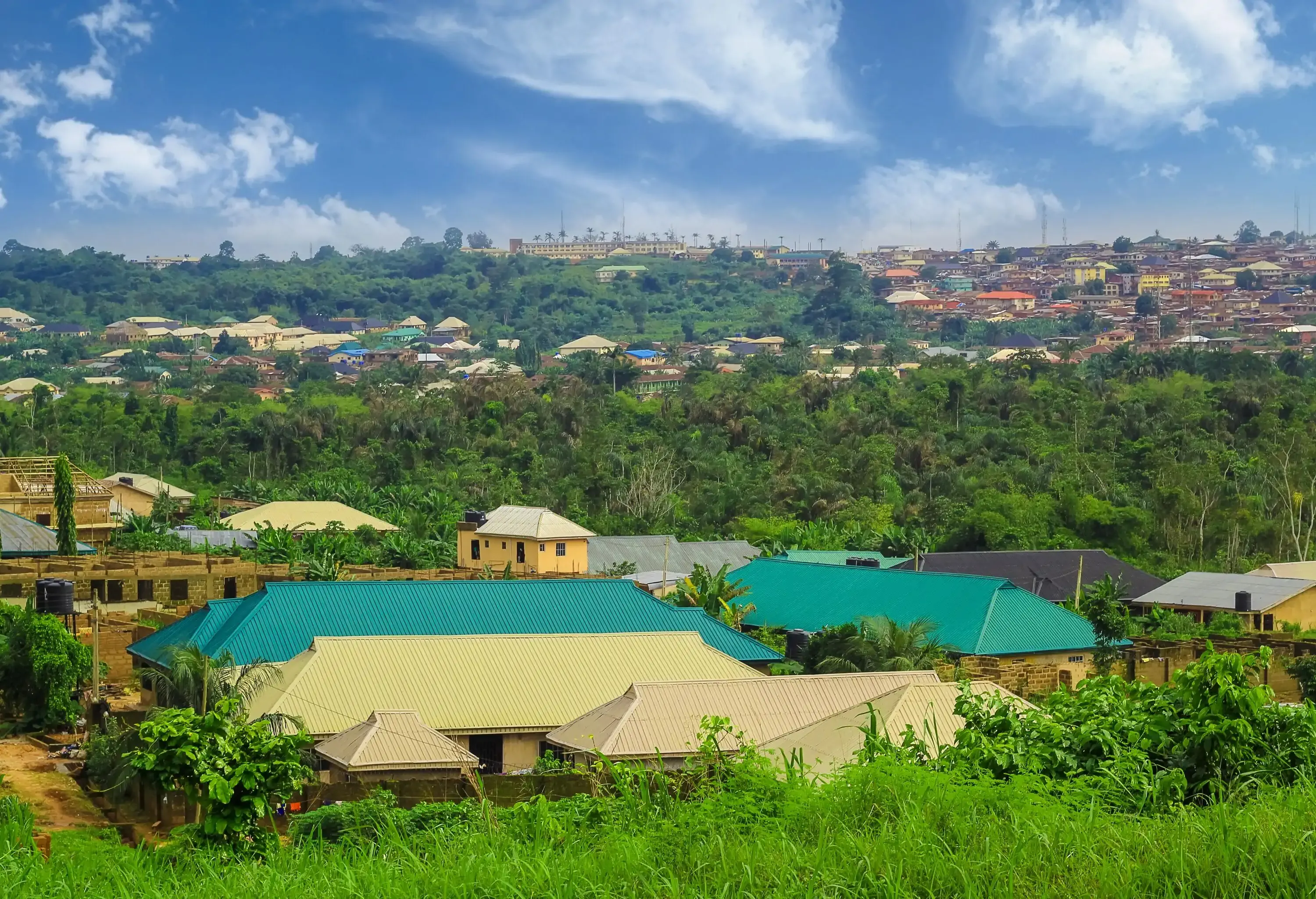 A residential neighbourhood of houses with colourful roofs and views of houses perched on hills amongst lush trees.
