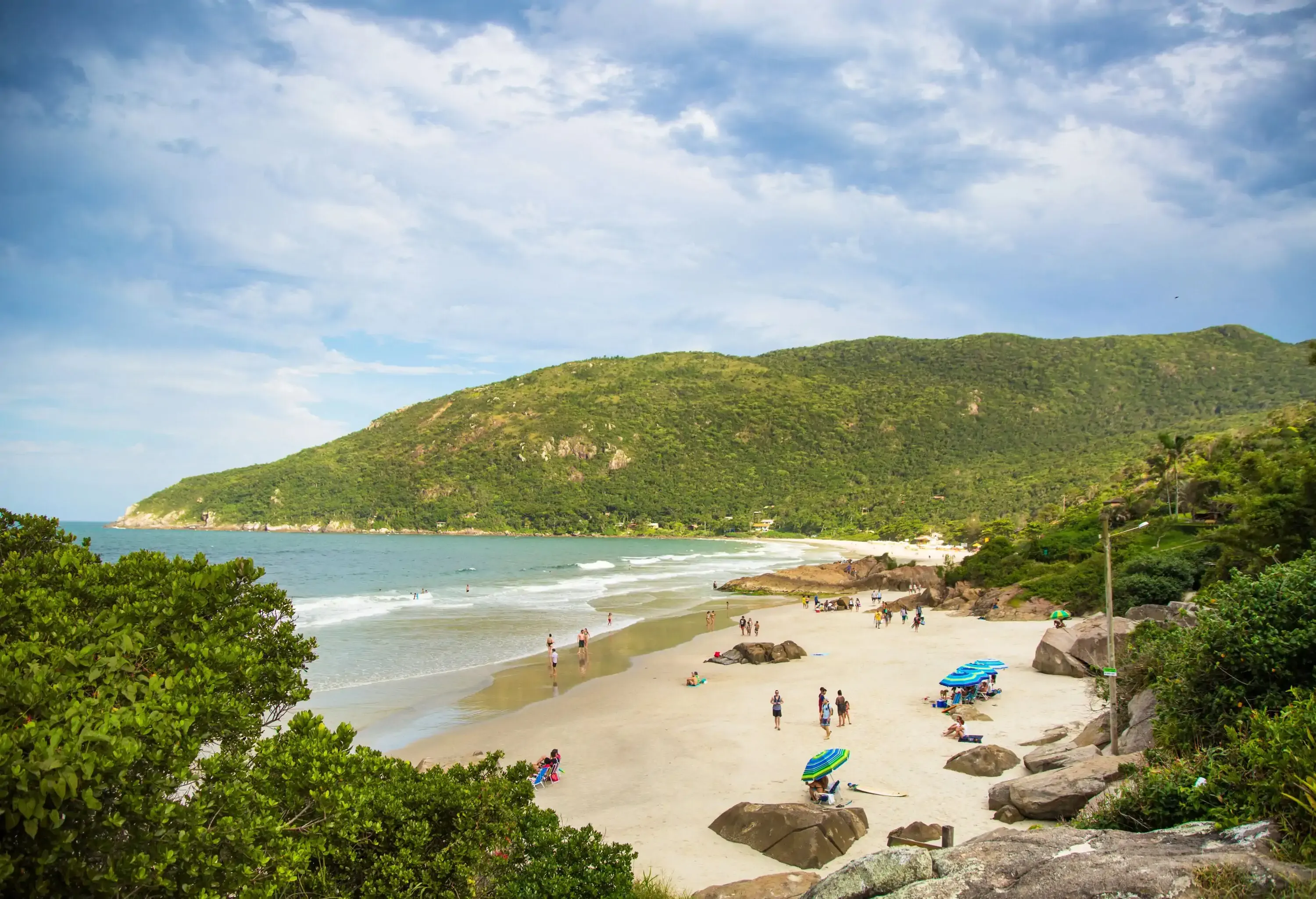 A pristine white sand beach, embraced by lush, verdant slopes.