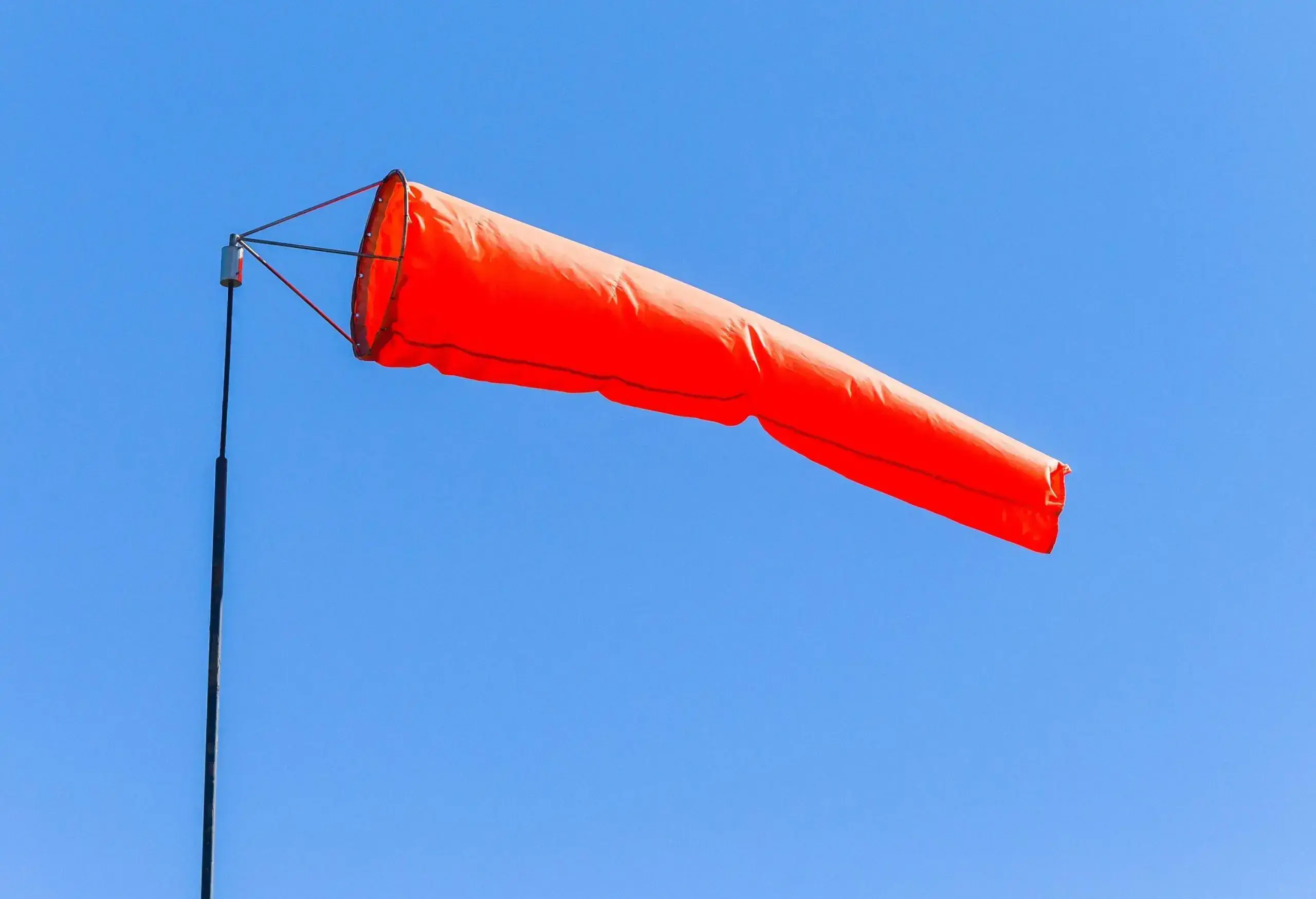 Airport Weather wind sock bright vibrant color against blue sky for flying aircraft pilot direction information.