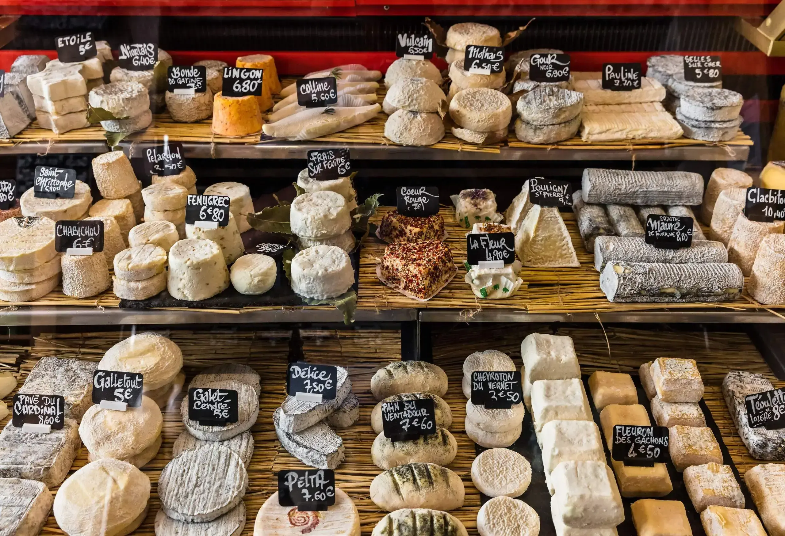 A display of assorted cheese with individual labels and pricing.