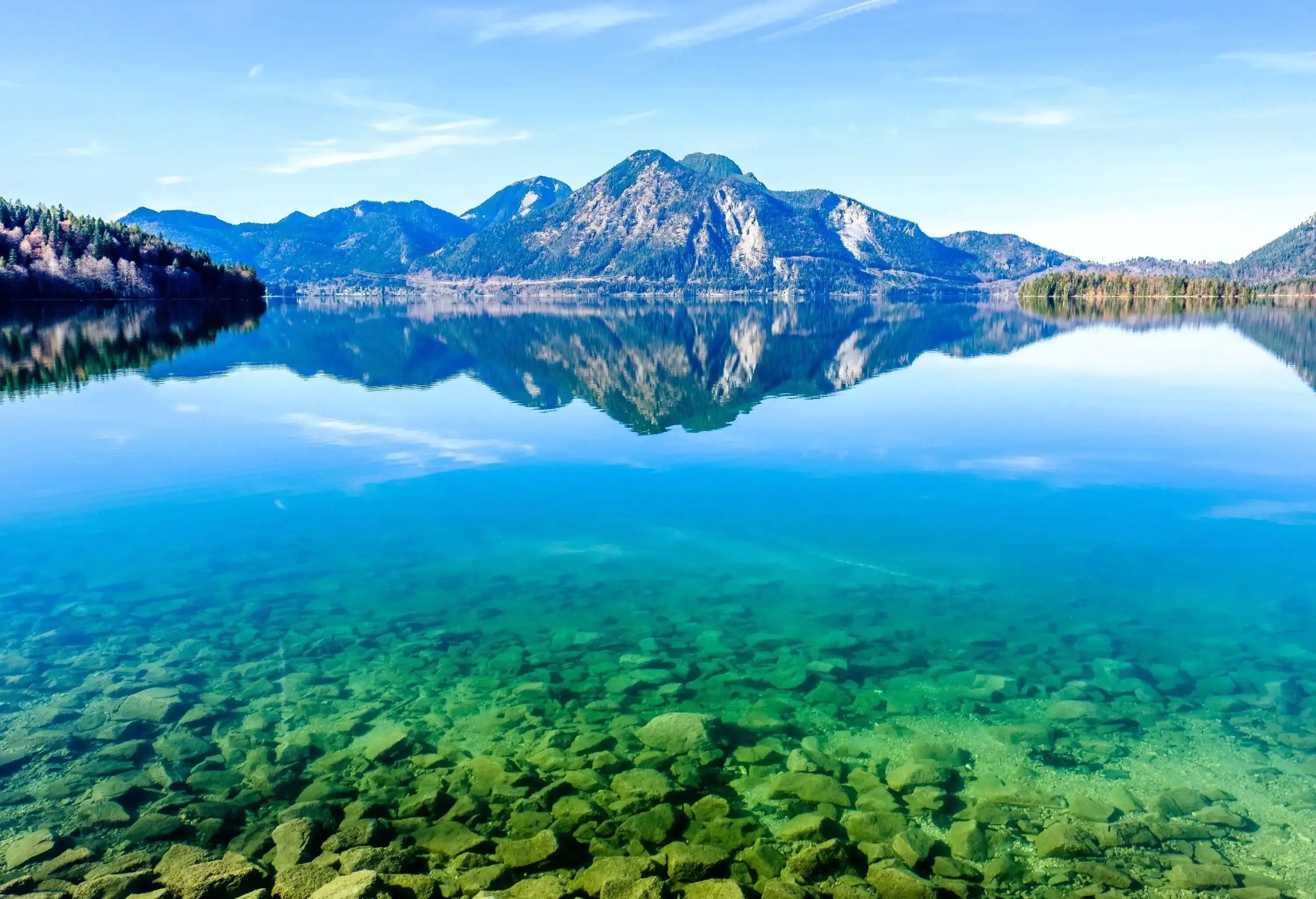 A clear turquoise lake with mountains in the background
