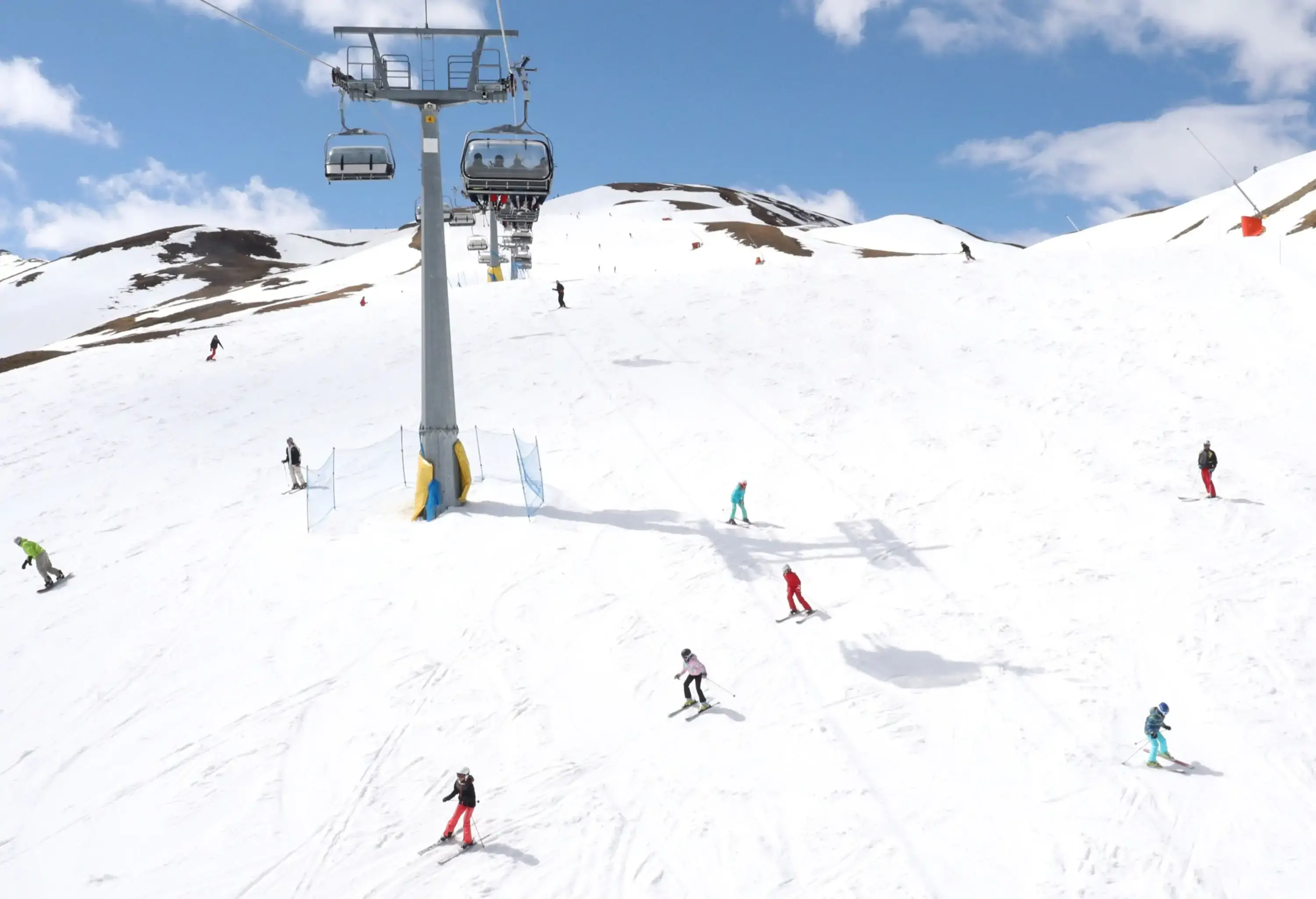 A ski slope landscape with cable cars hanging above the skiers.