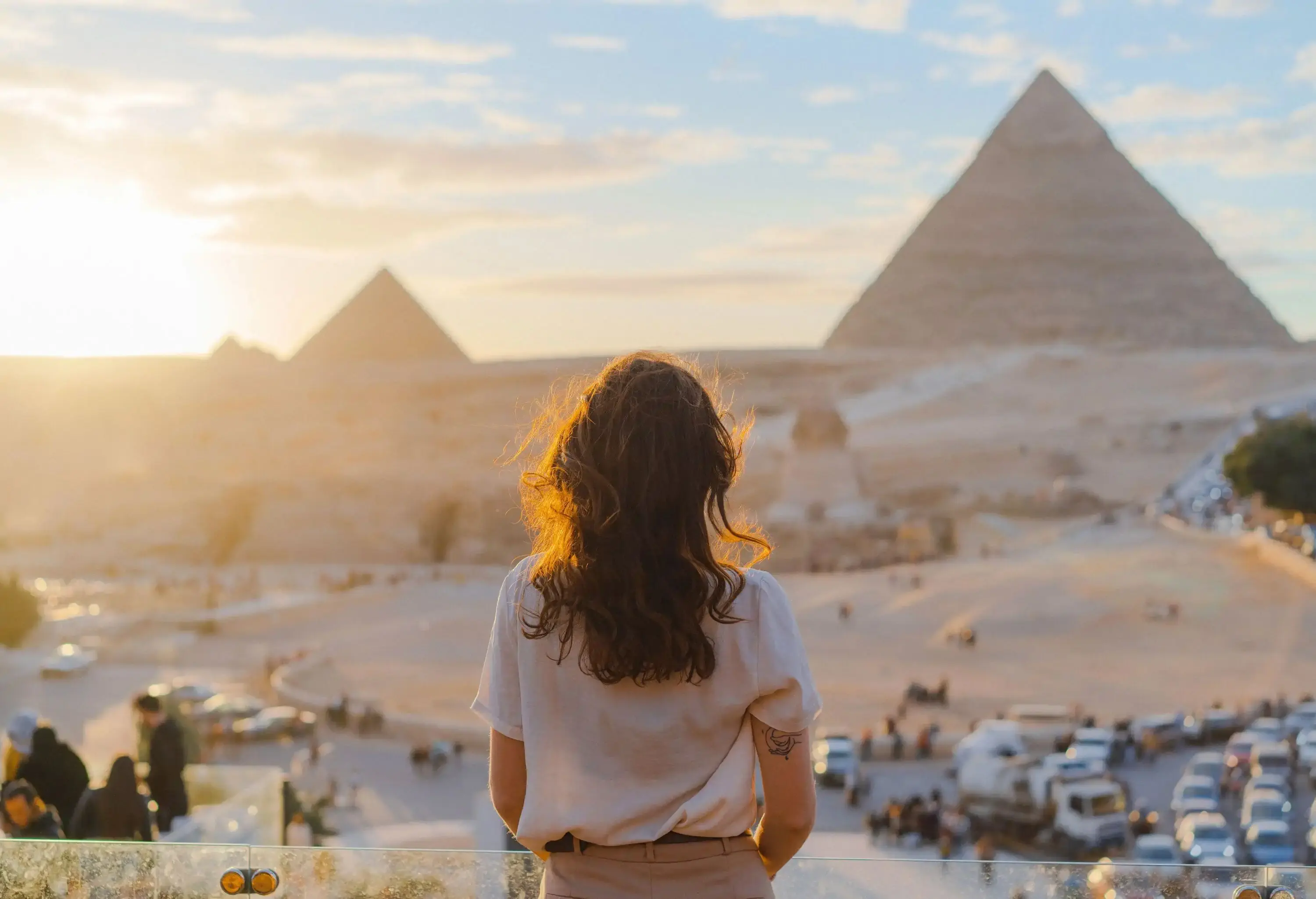 Young Caucasian woman standing on the terrace on the background of Giza pyramids