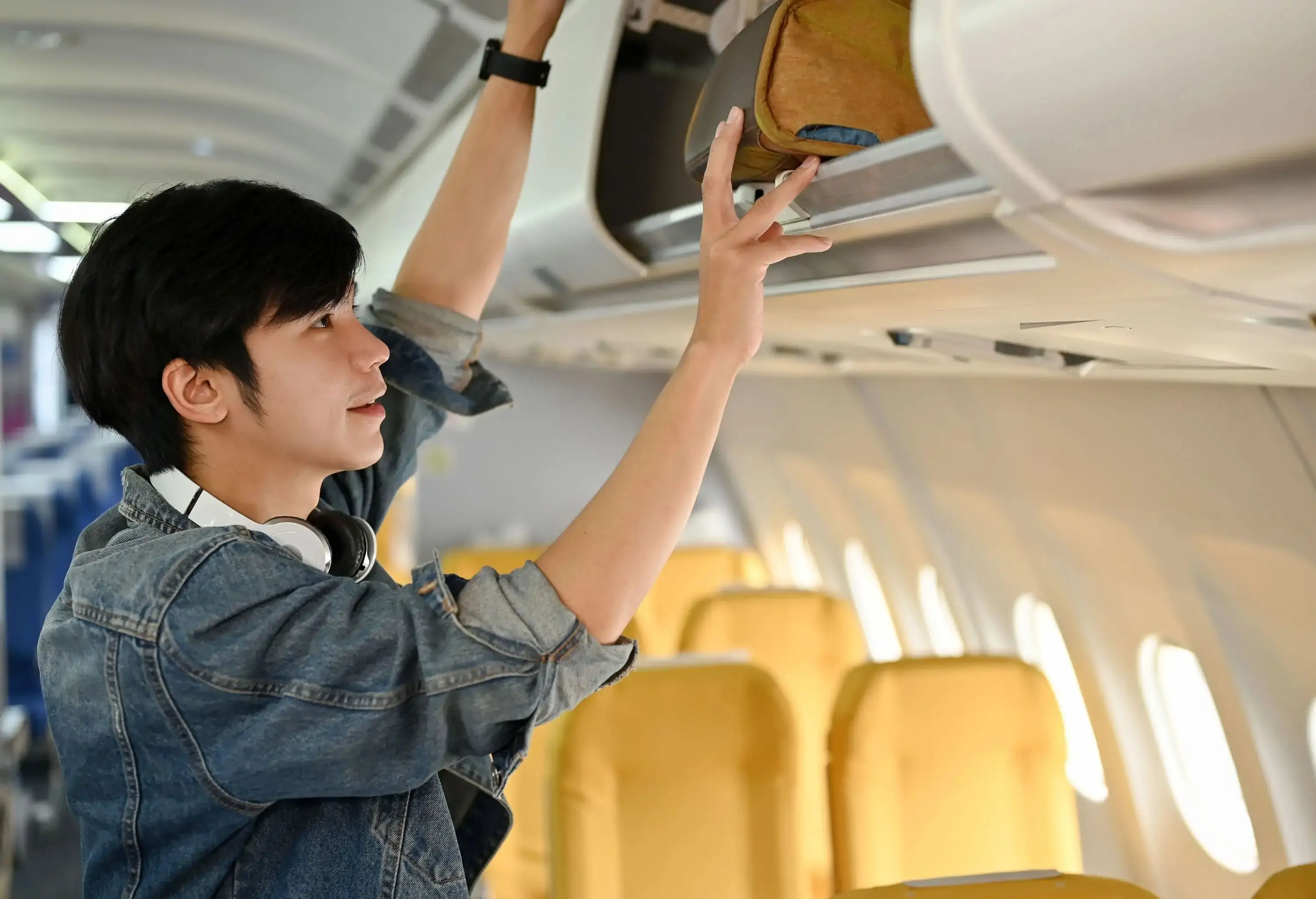 A man placing his cabin bag in the overhead