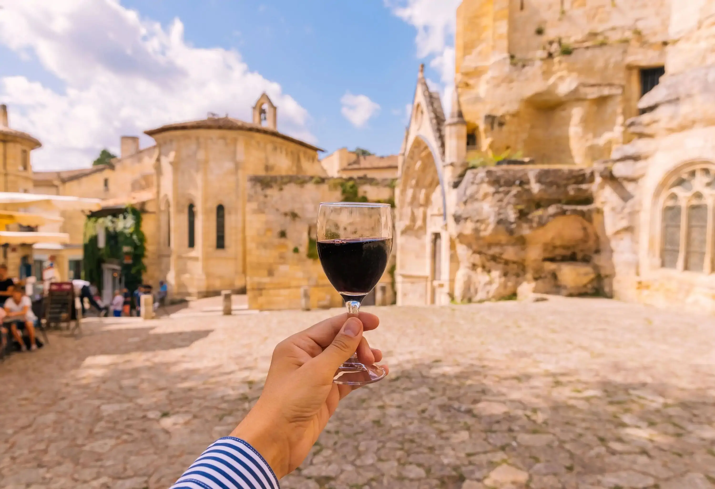 A hand holding a glass of wine.