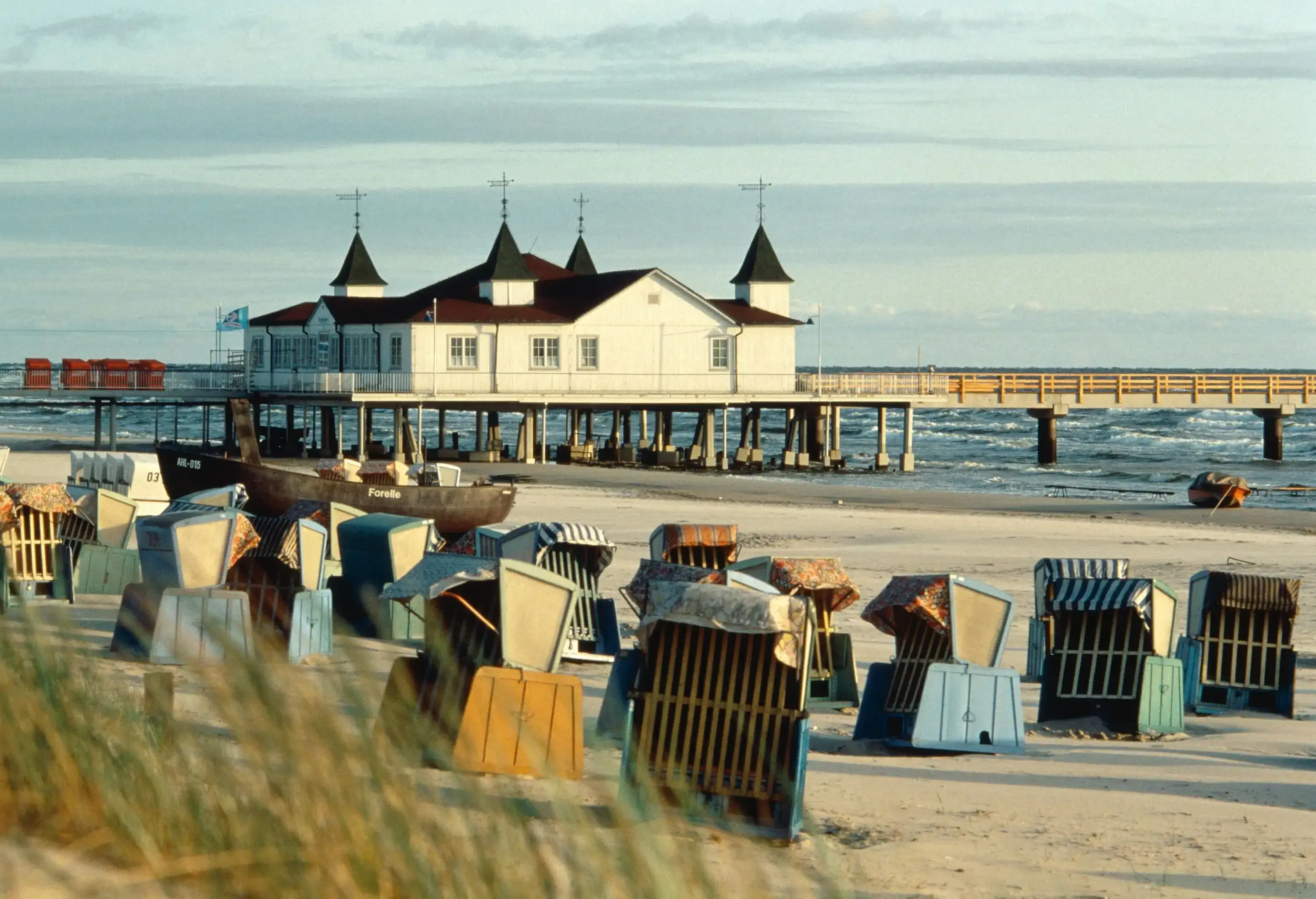 Rows of roofed deckchairs on the shore of the beach overlooking the marina.