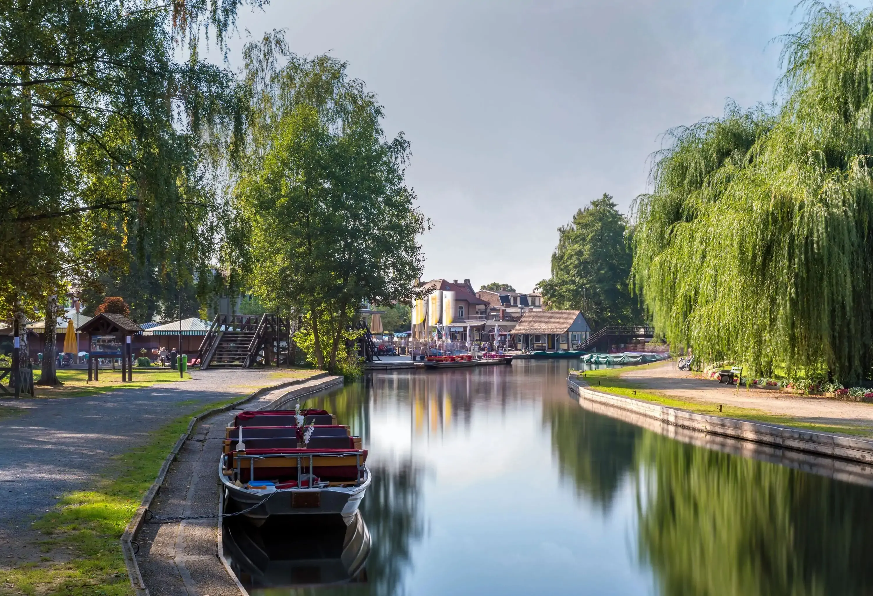 A passenger boat was moored along the riverbank, which was lined with walkways and trees.