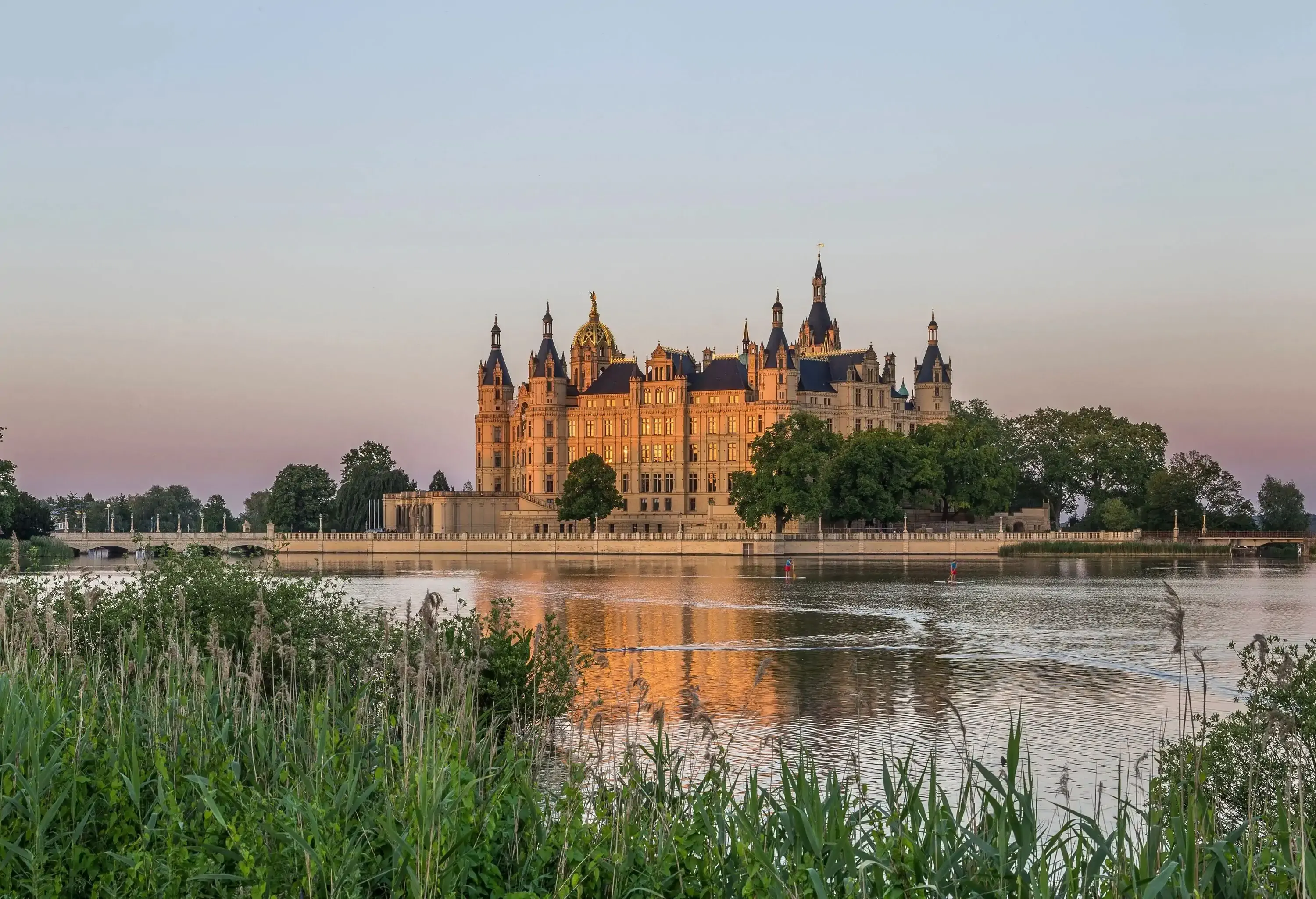 A fortified castle with a beautiful landscape of a lake and forests.