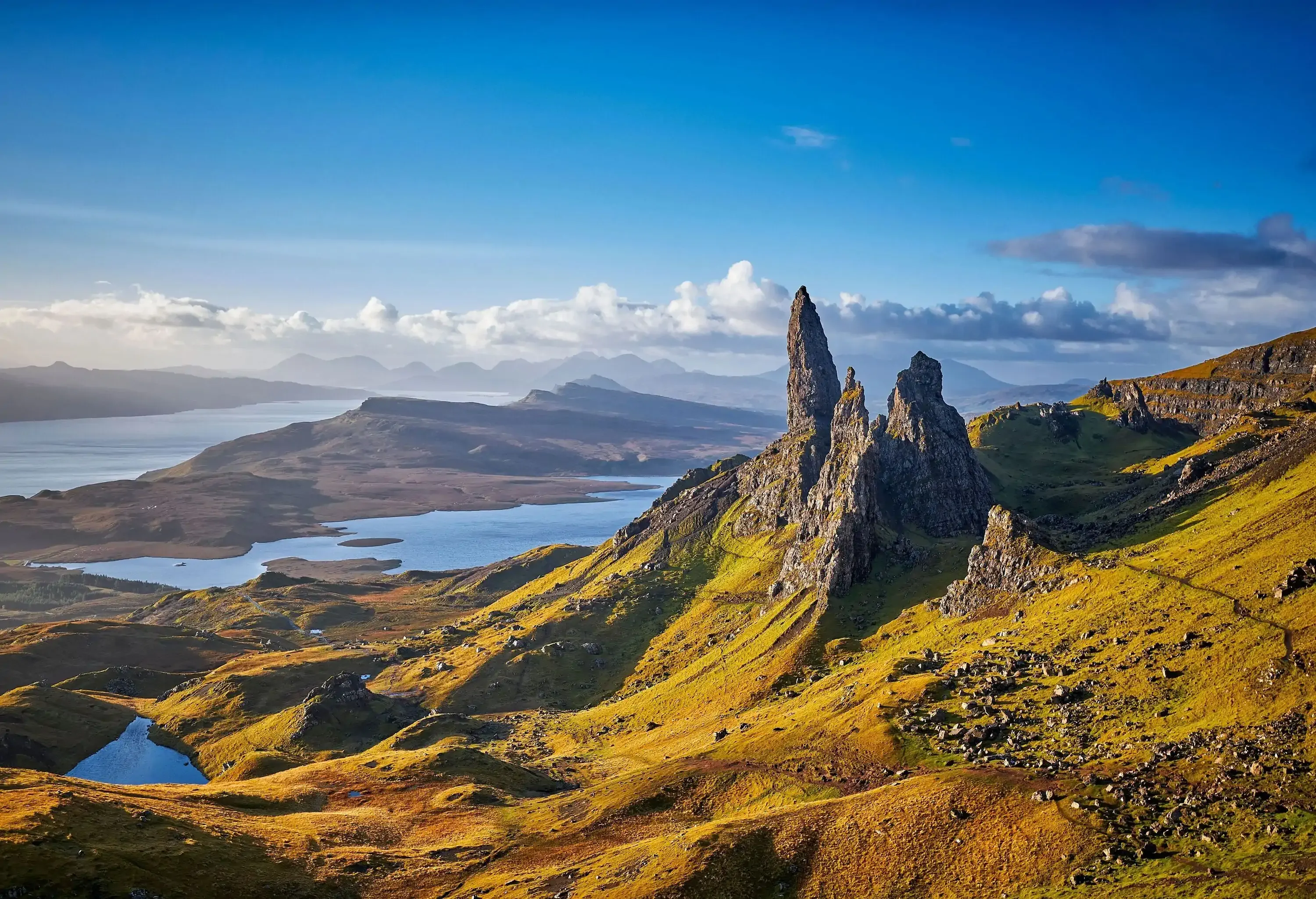 A sloping landscape with jagged peaks that overlooks a lake in the distance.