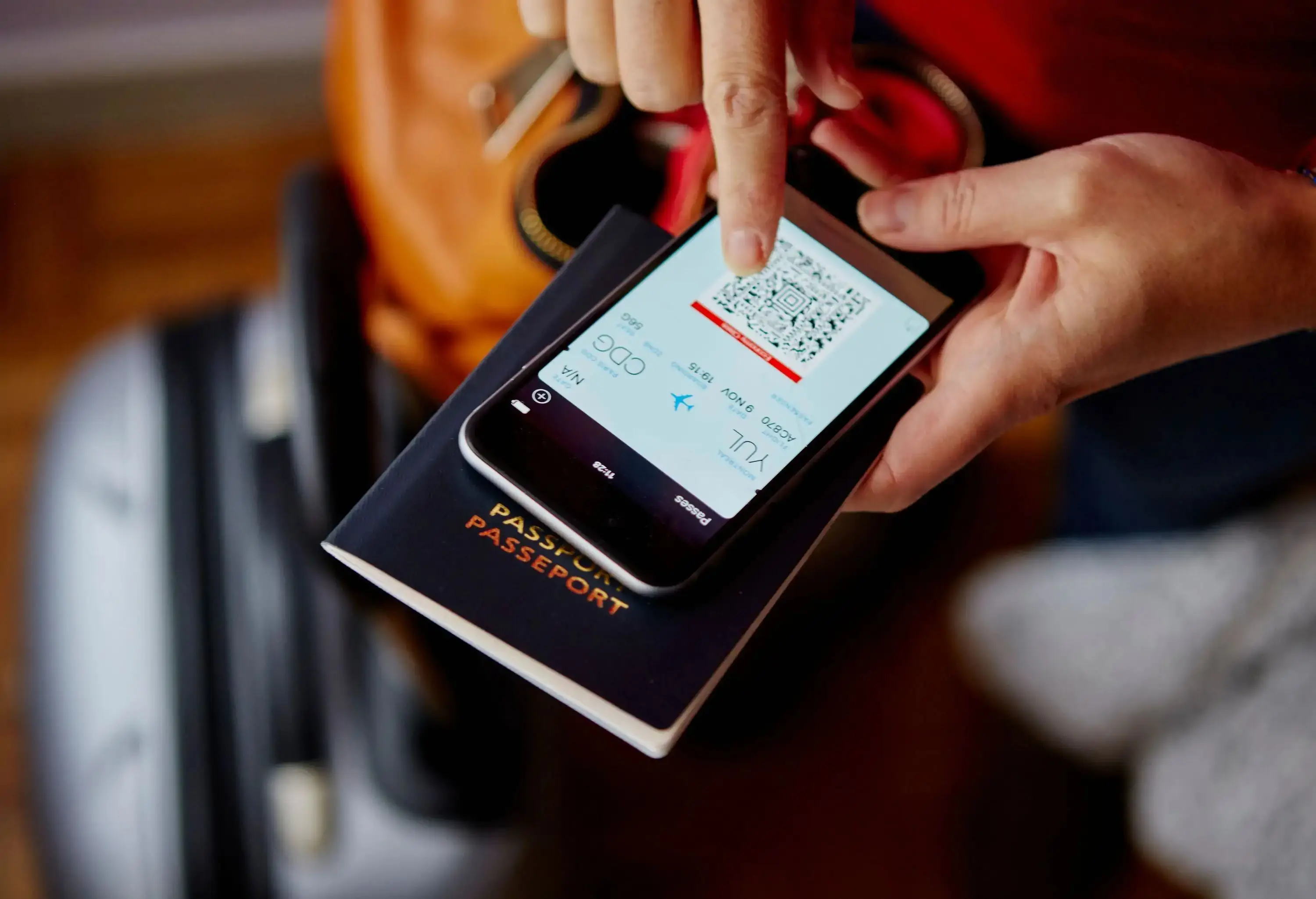 A person checks his flight QR code on his mobile device on top of his passport.