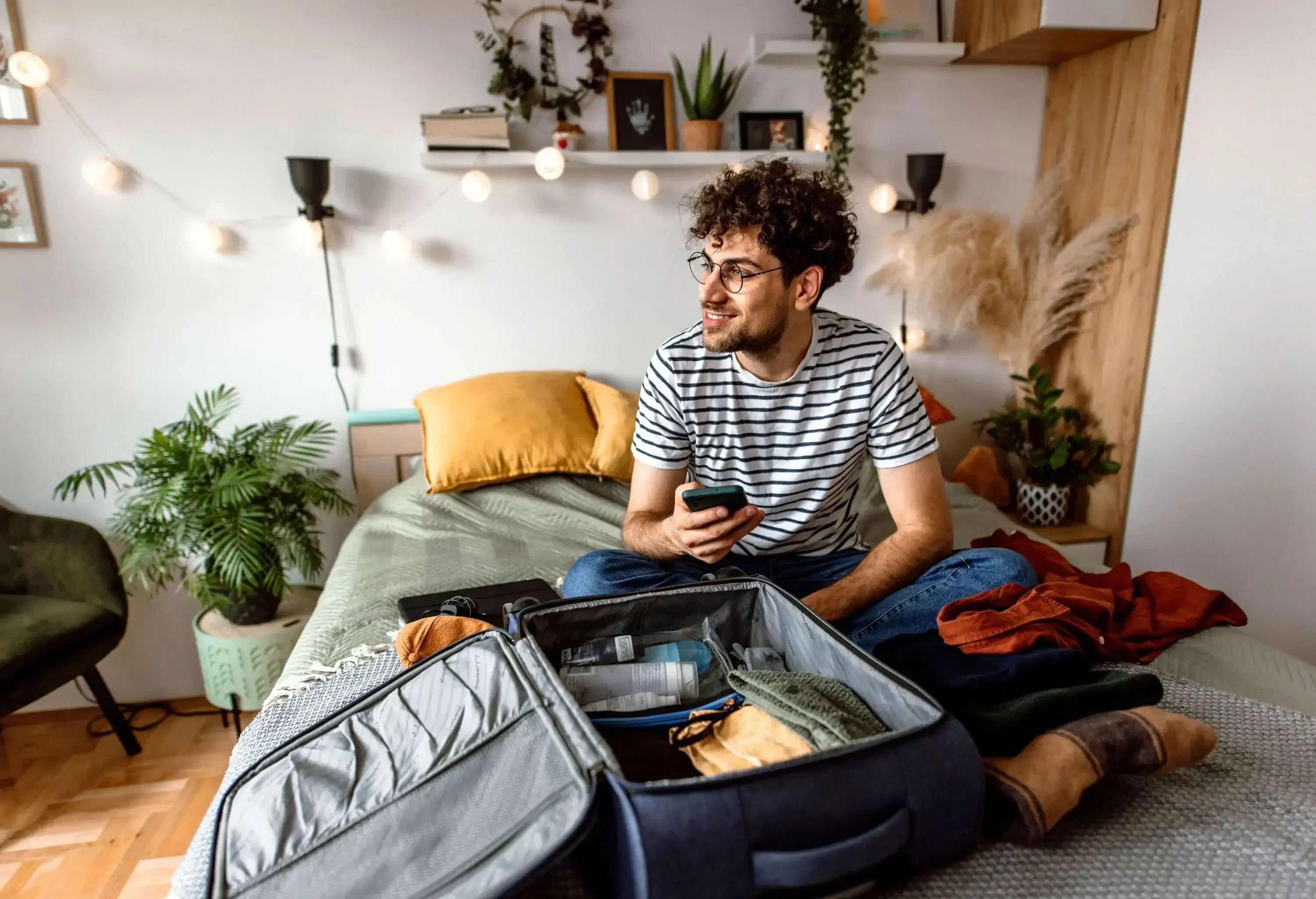 A man sitting in his bedroom, PACKING AND PREPAPRING for a trip.