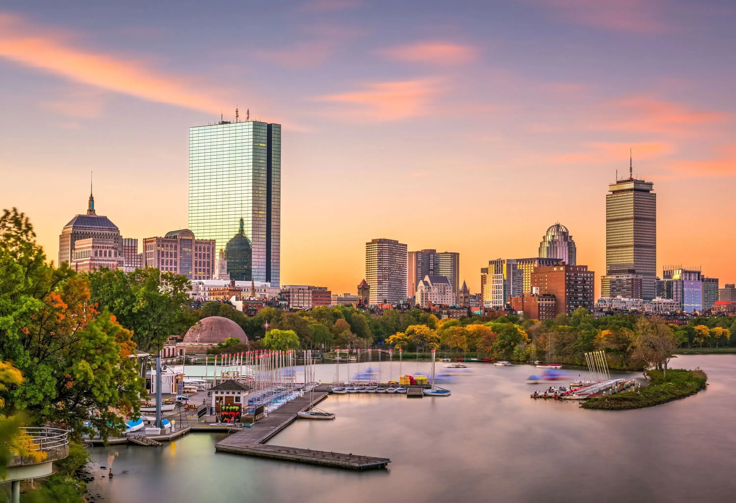 A serene memorial park on the river, framed by a captivating modern cityscape featuring towering skyscrapers, set against a picturesque twilight sky.