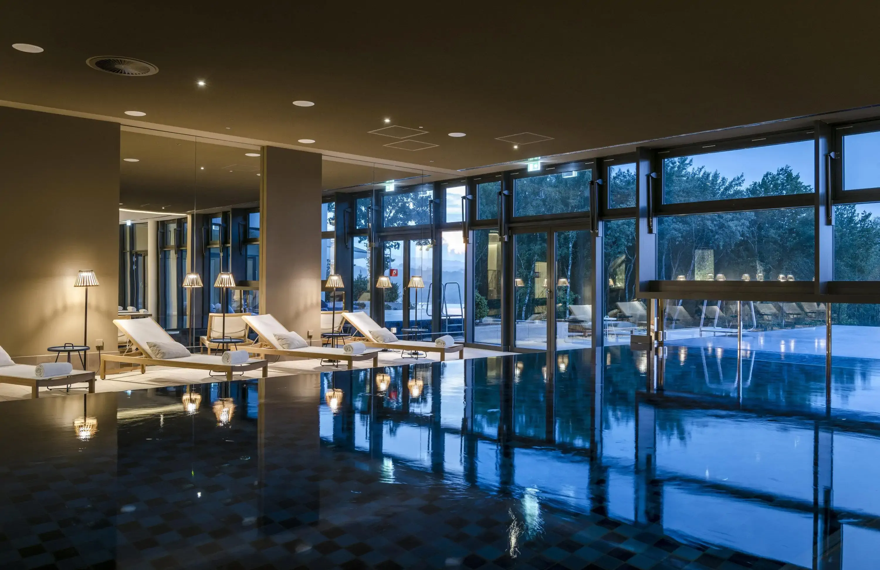 Contemporary indoor pool and spa chairs at dusk