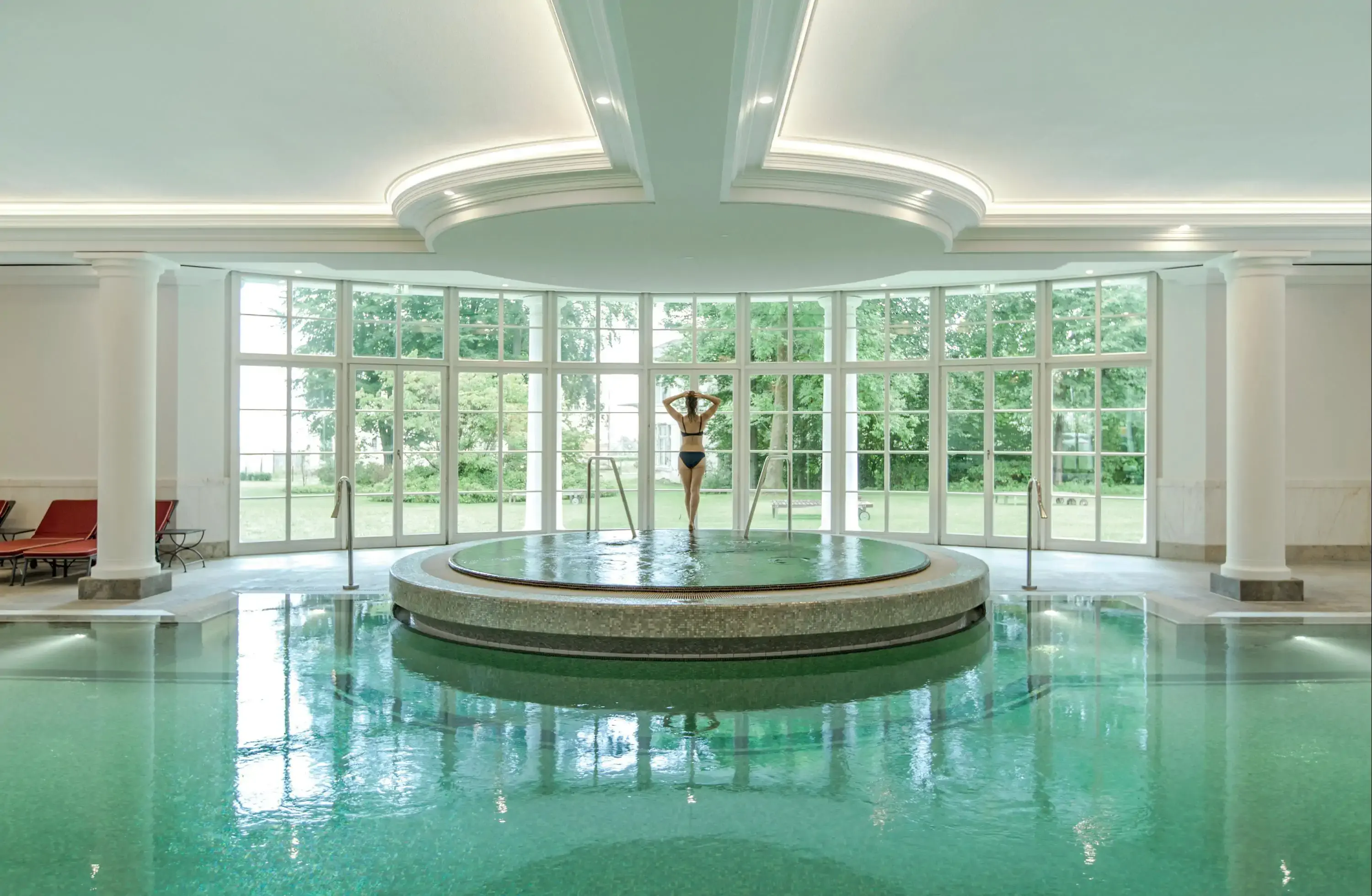 Contemporary indoor pool with circular platform and woman standing in the middle