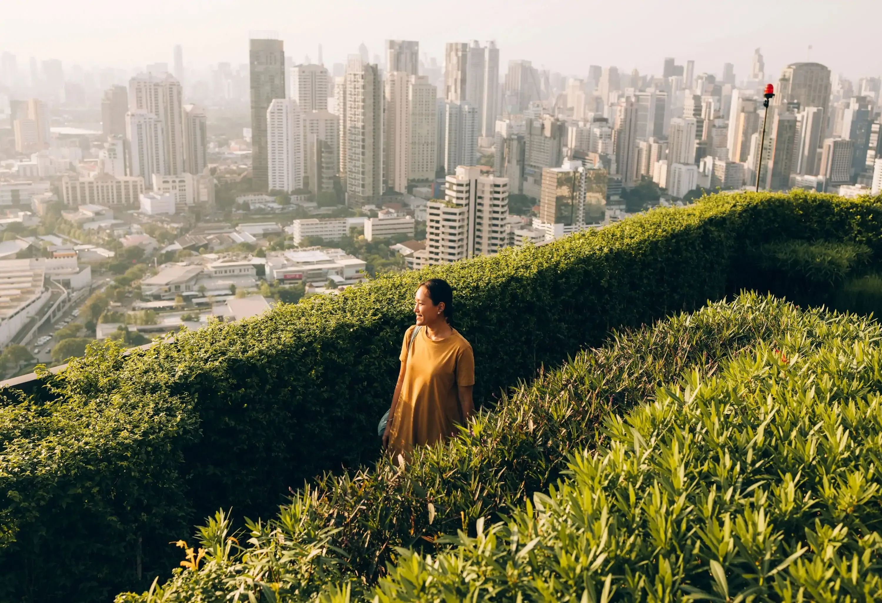 A woman enjoying the view of the city from a rooftop garden.